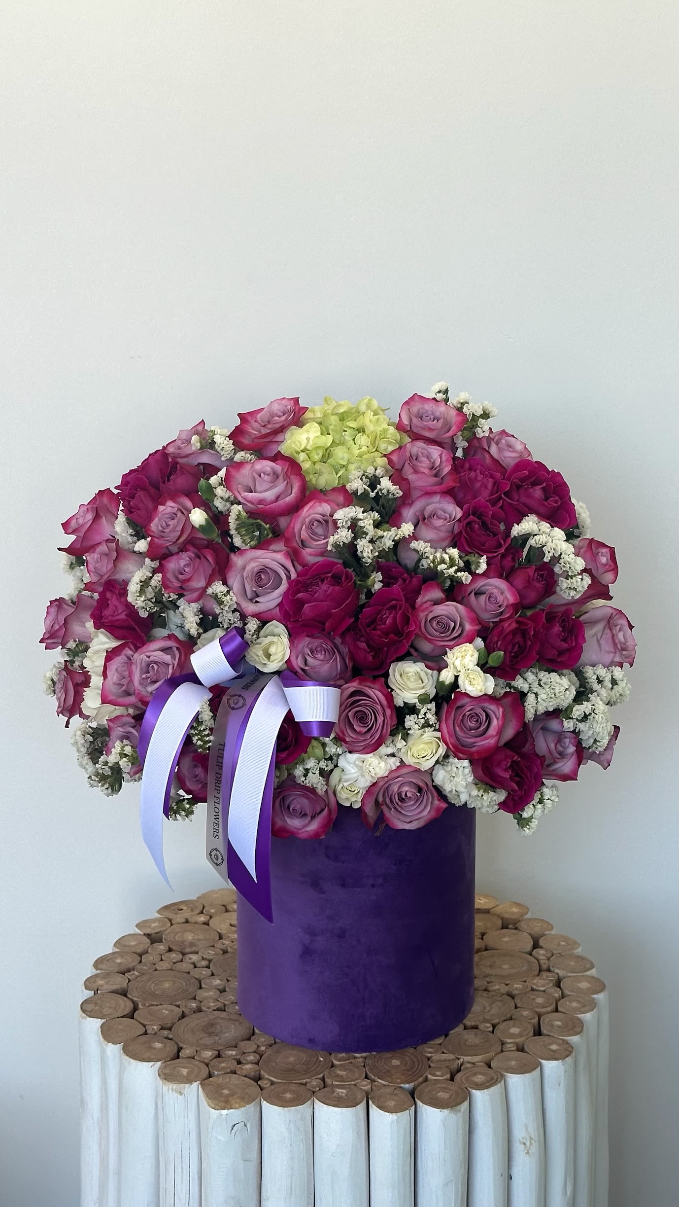 Large bouquet of pink and purple roses in a purple box with ribbon