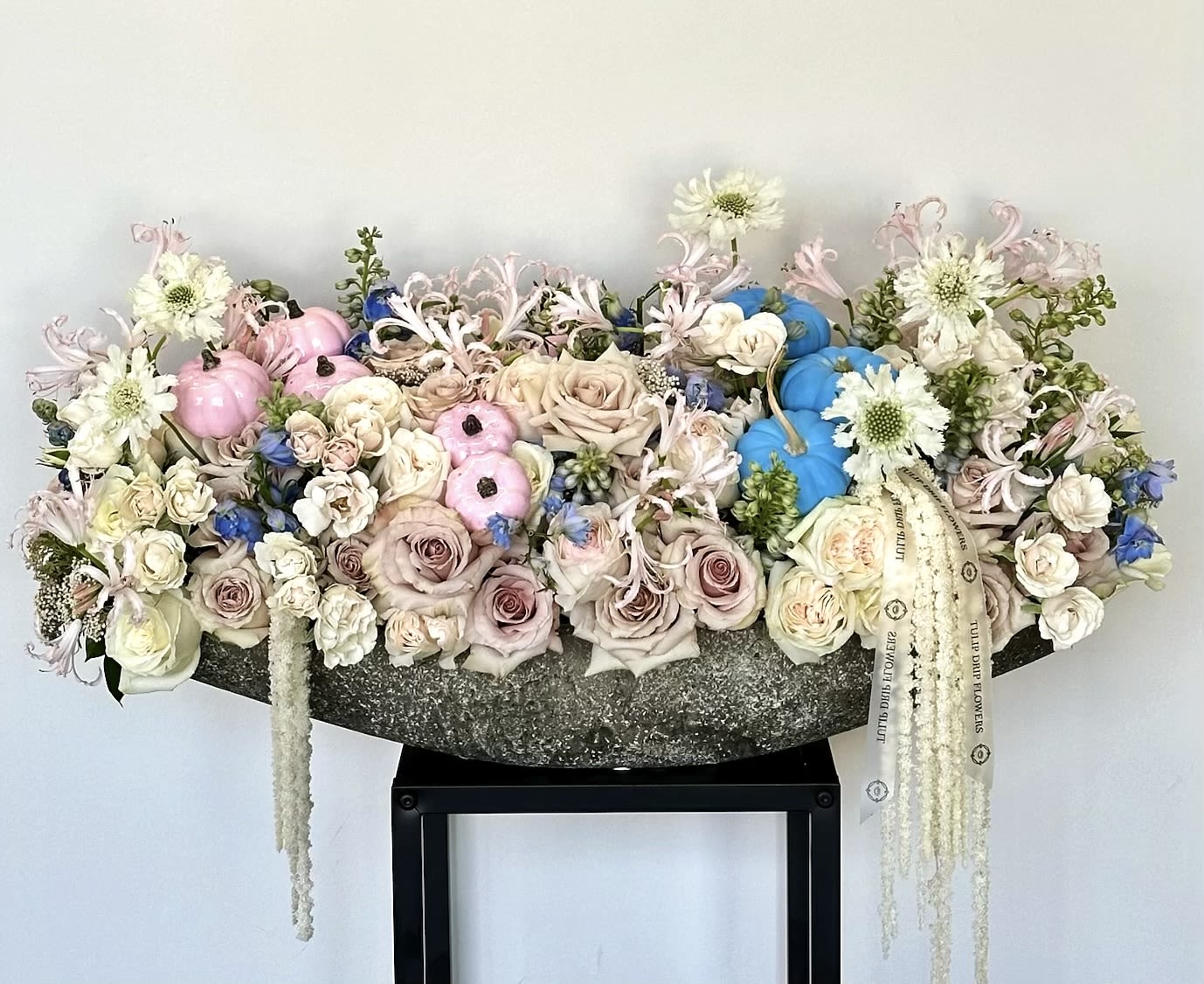Large pastel floral arrangement with roses, white blooms, and decorative pumpkins