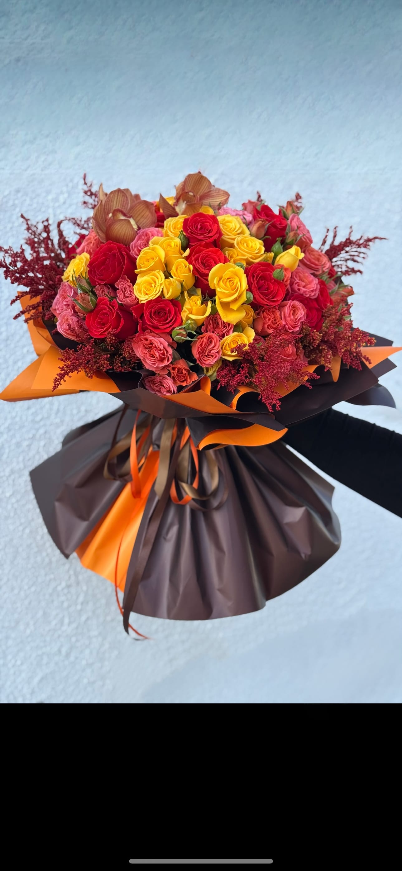 Bouquet of red and yellow roses wrapped in brown and orange paper