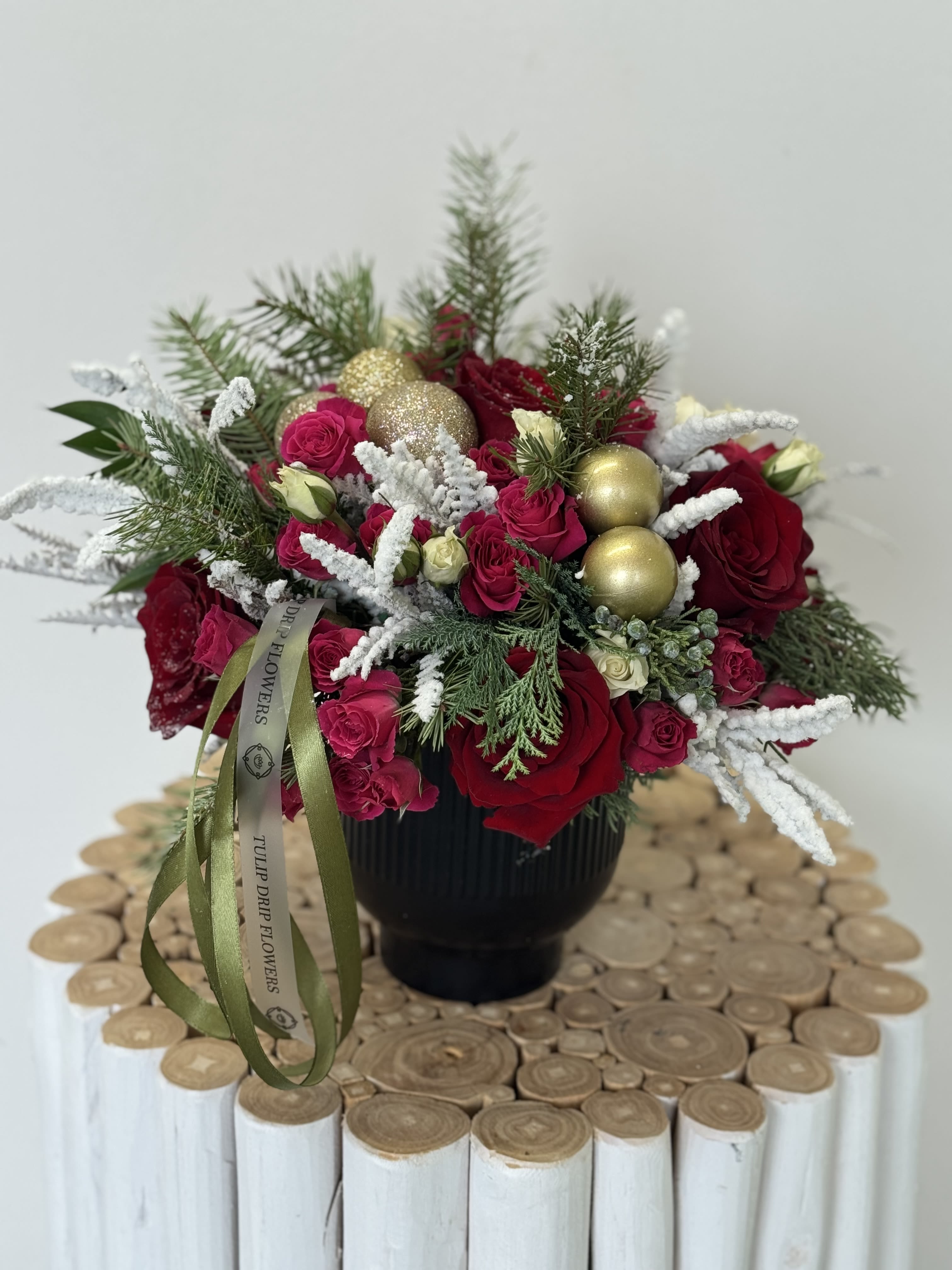 Red roses and pink spray roses in a black vase with gold ornaments