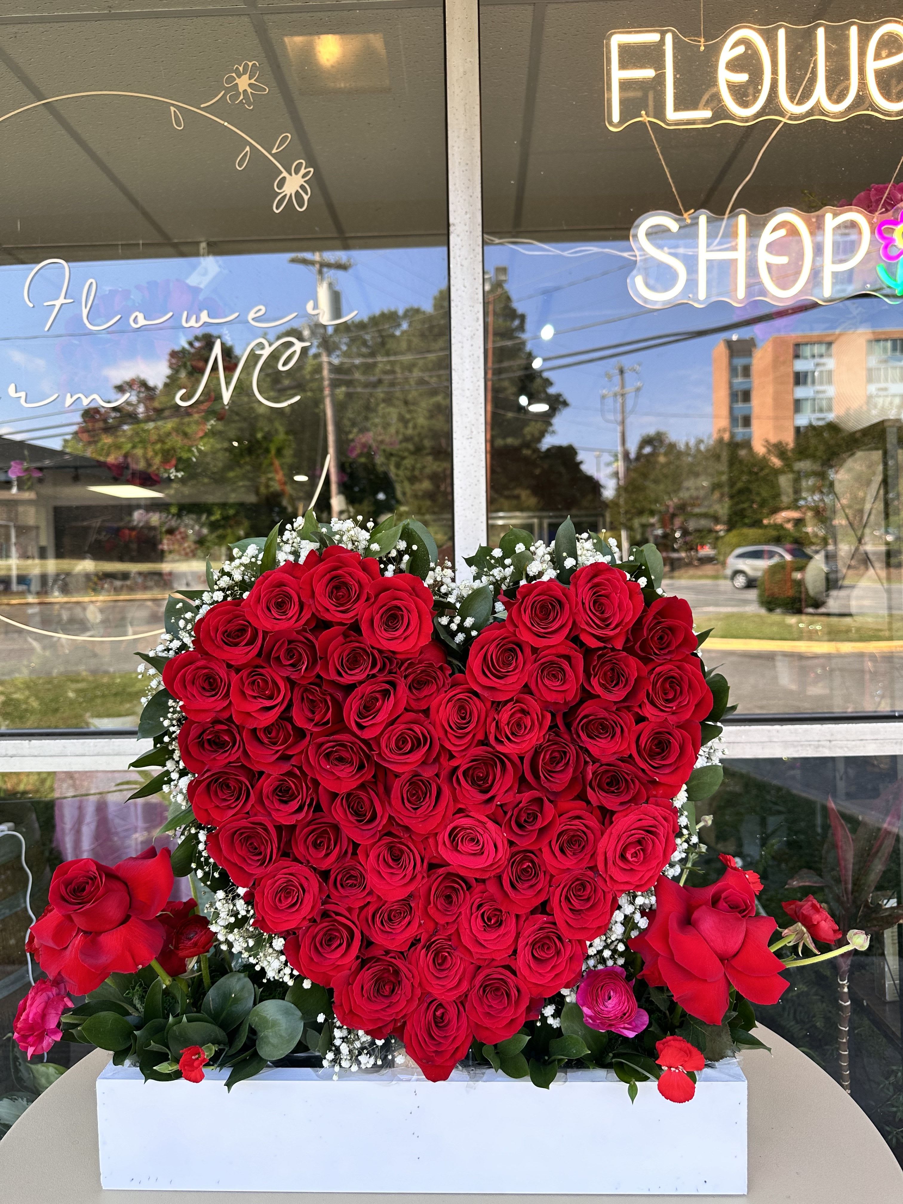 Heart-shaped red rose arrangement in a white box