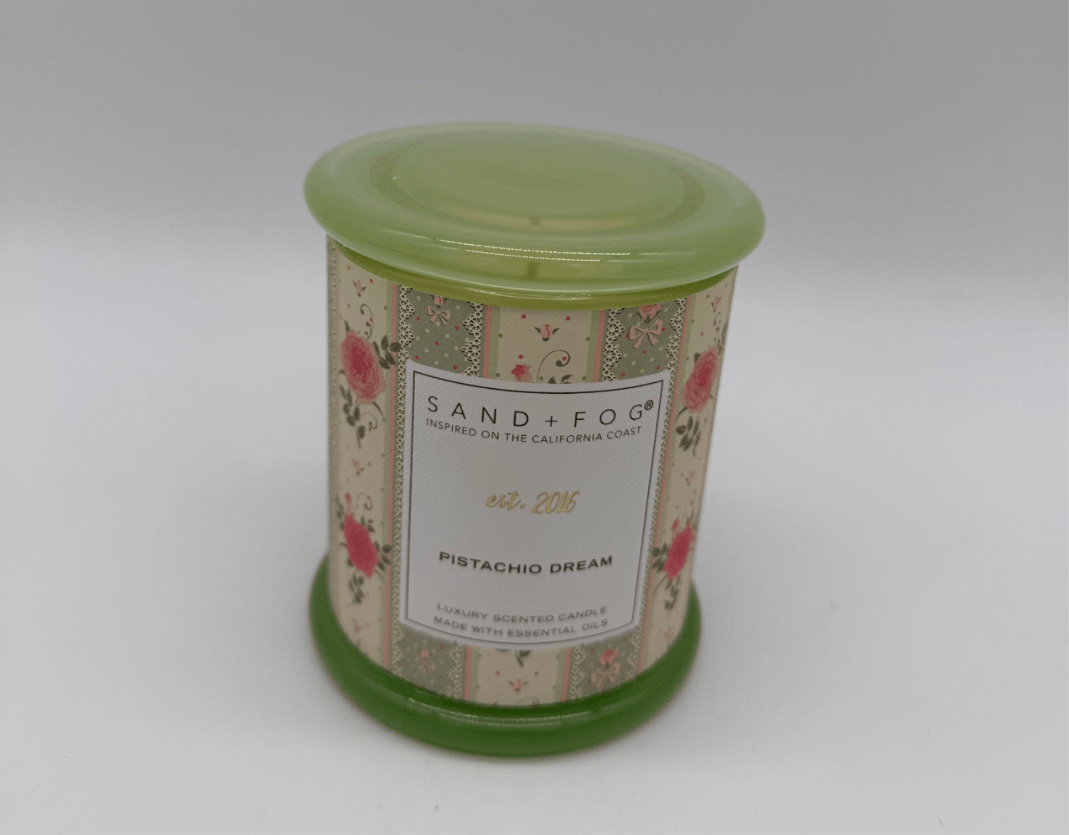 A floral-patterned scented candle in a green tin container