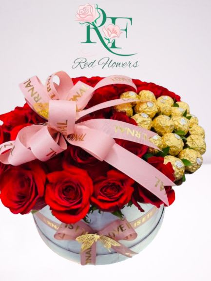 Red roses and gold-wrapped chocolates in a round glass box with pink ribbon