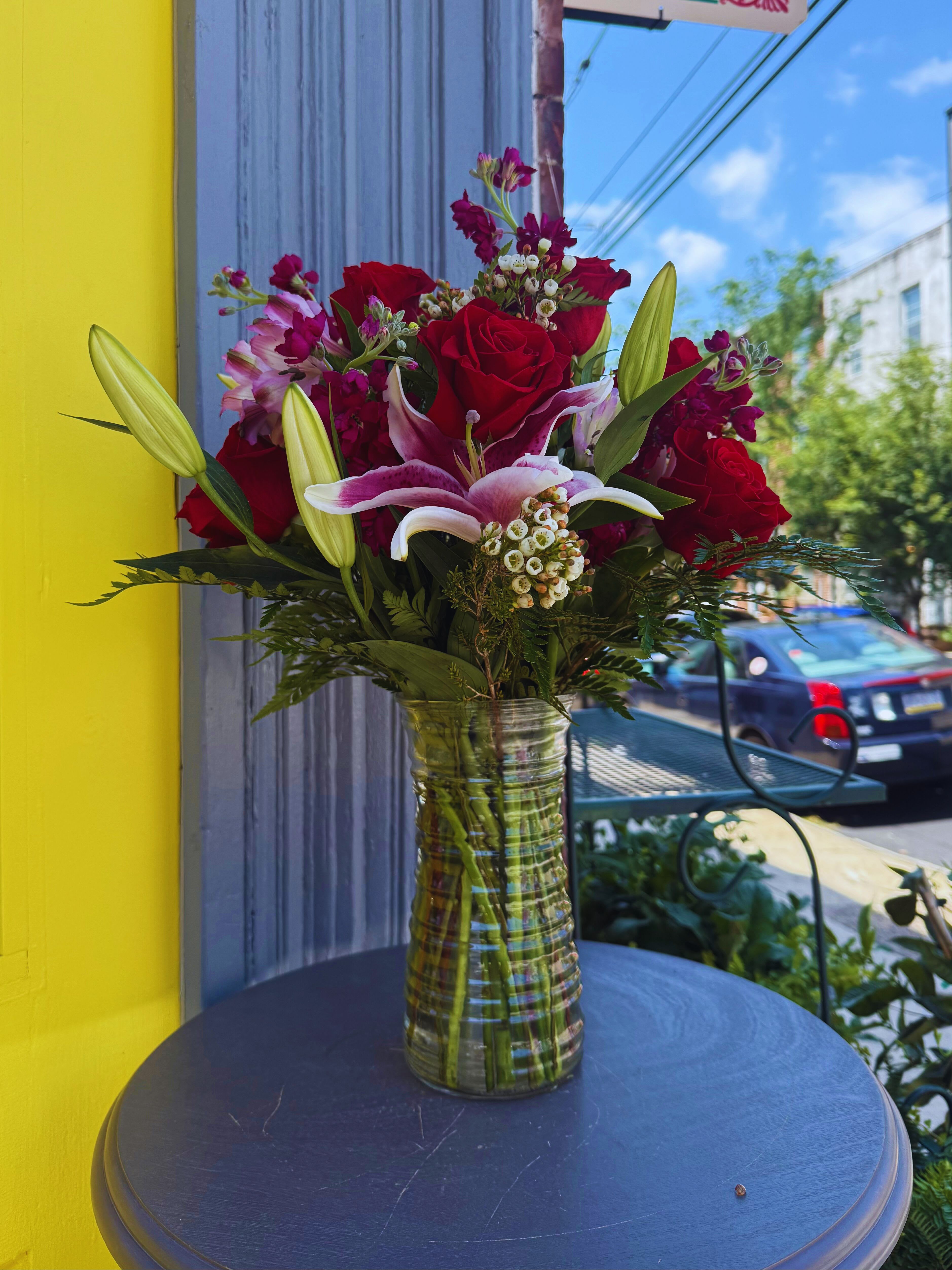 Bouquet of red roses and pink lilies in a clear glass vase