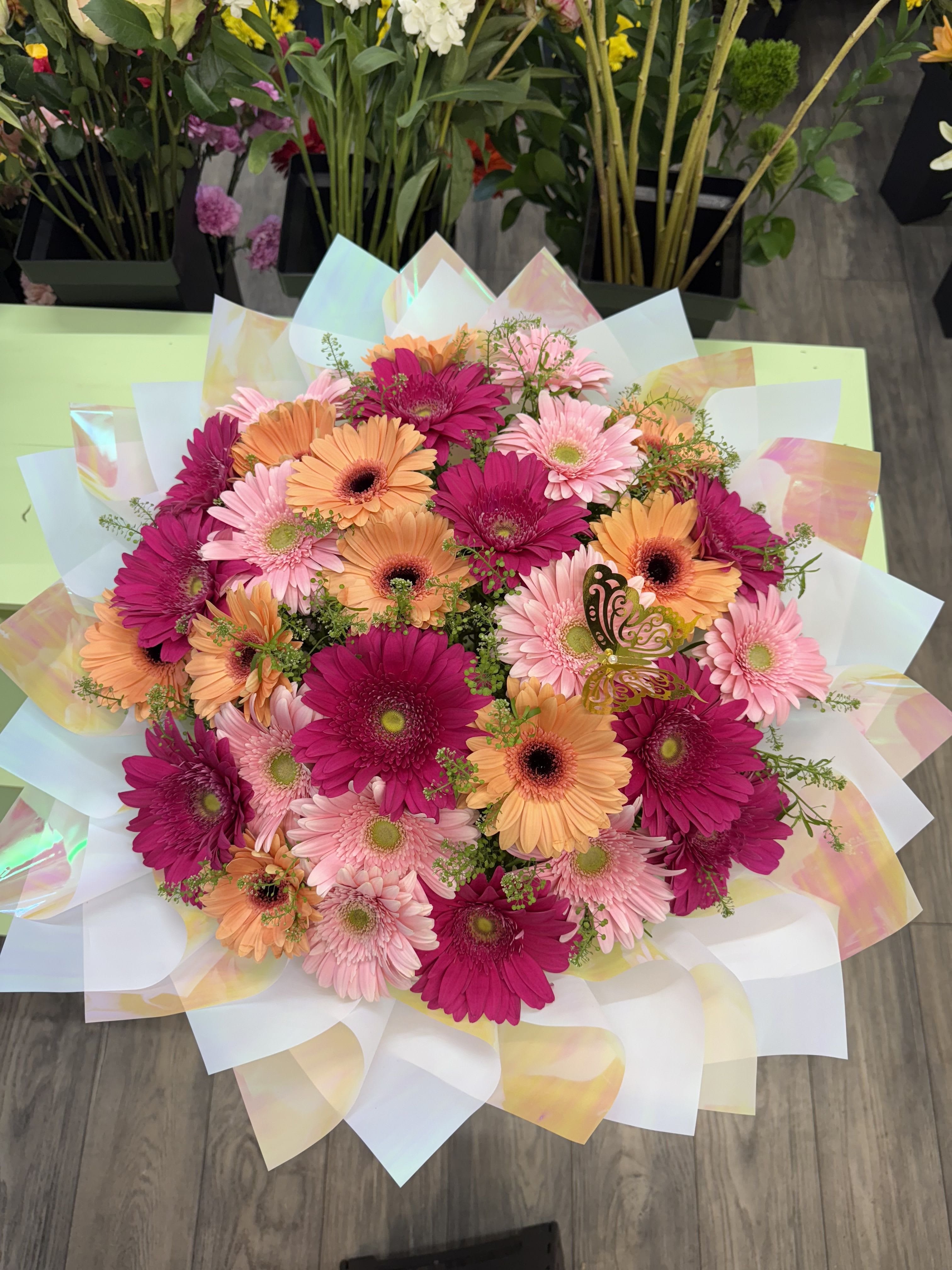 Bouquet of pink and orange gerbera daisies wrapped in iridescent paper