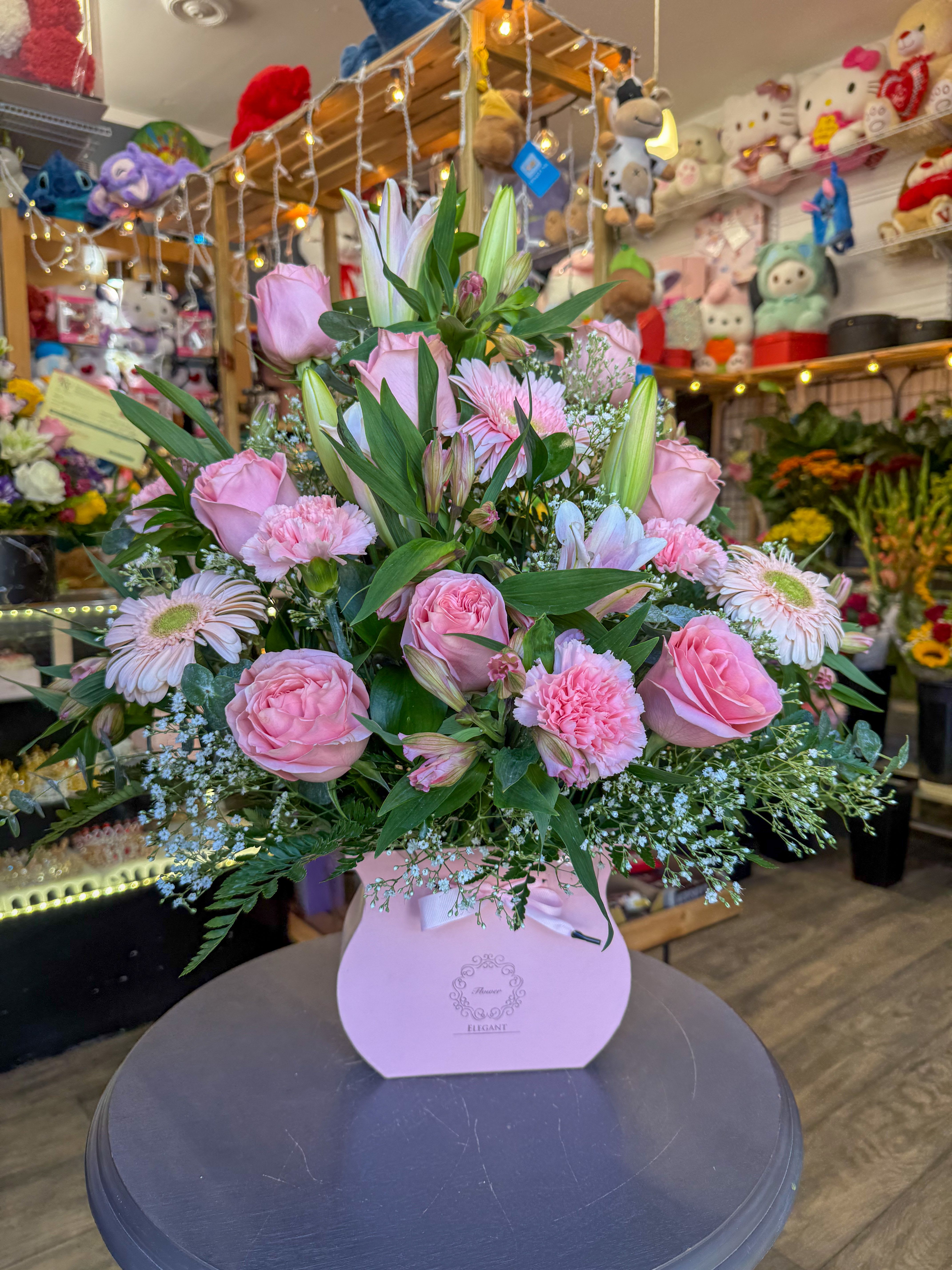 Pink roses and lilies arranged in a pink gift box