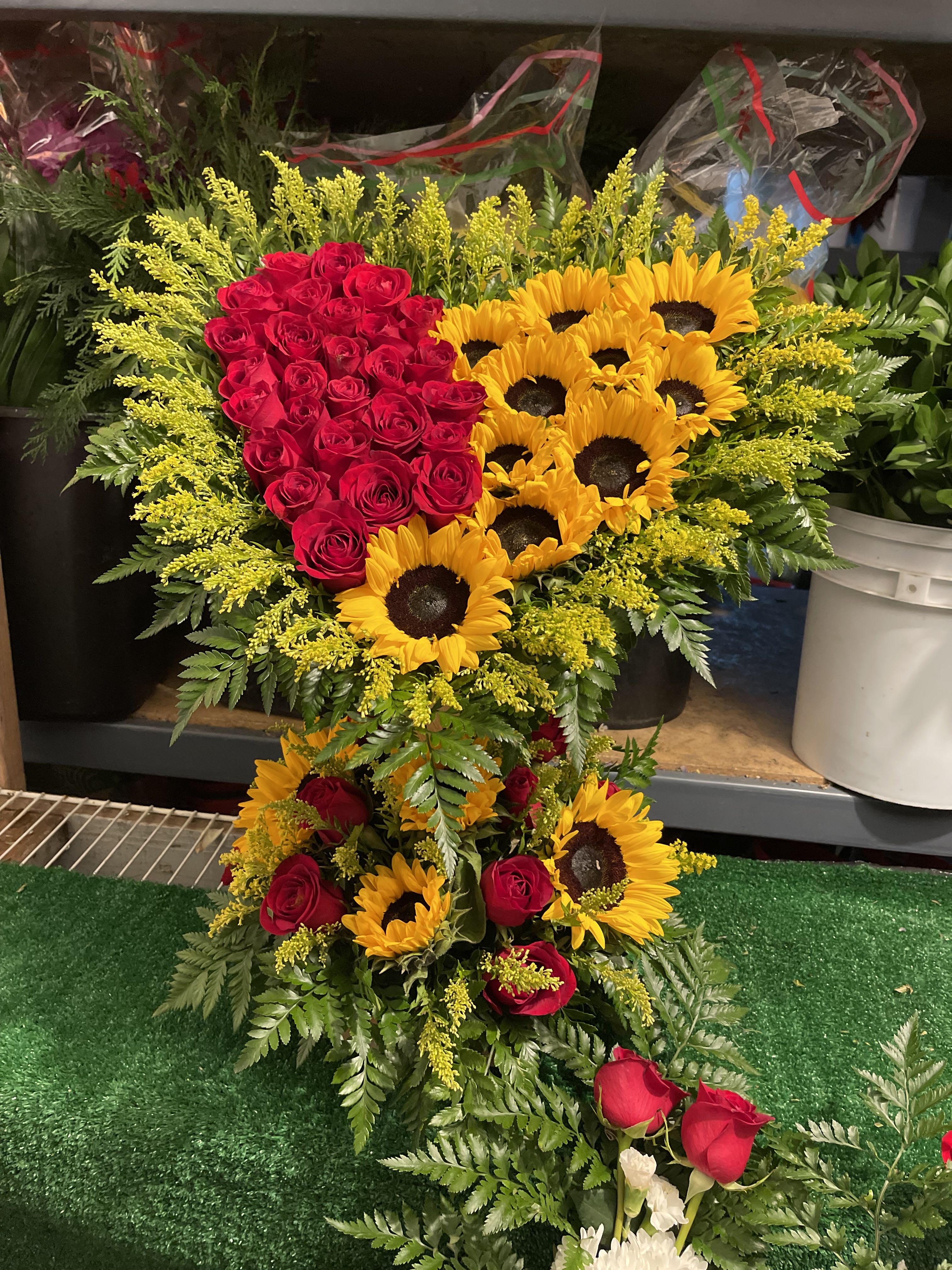 Heart-shaped arrangement of red roses and yellow sunflowers