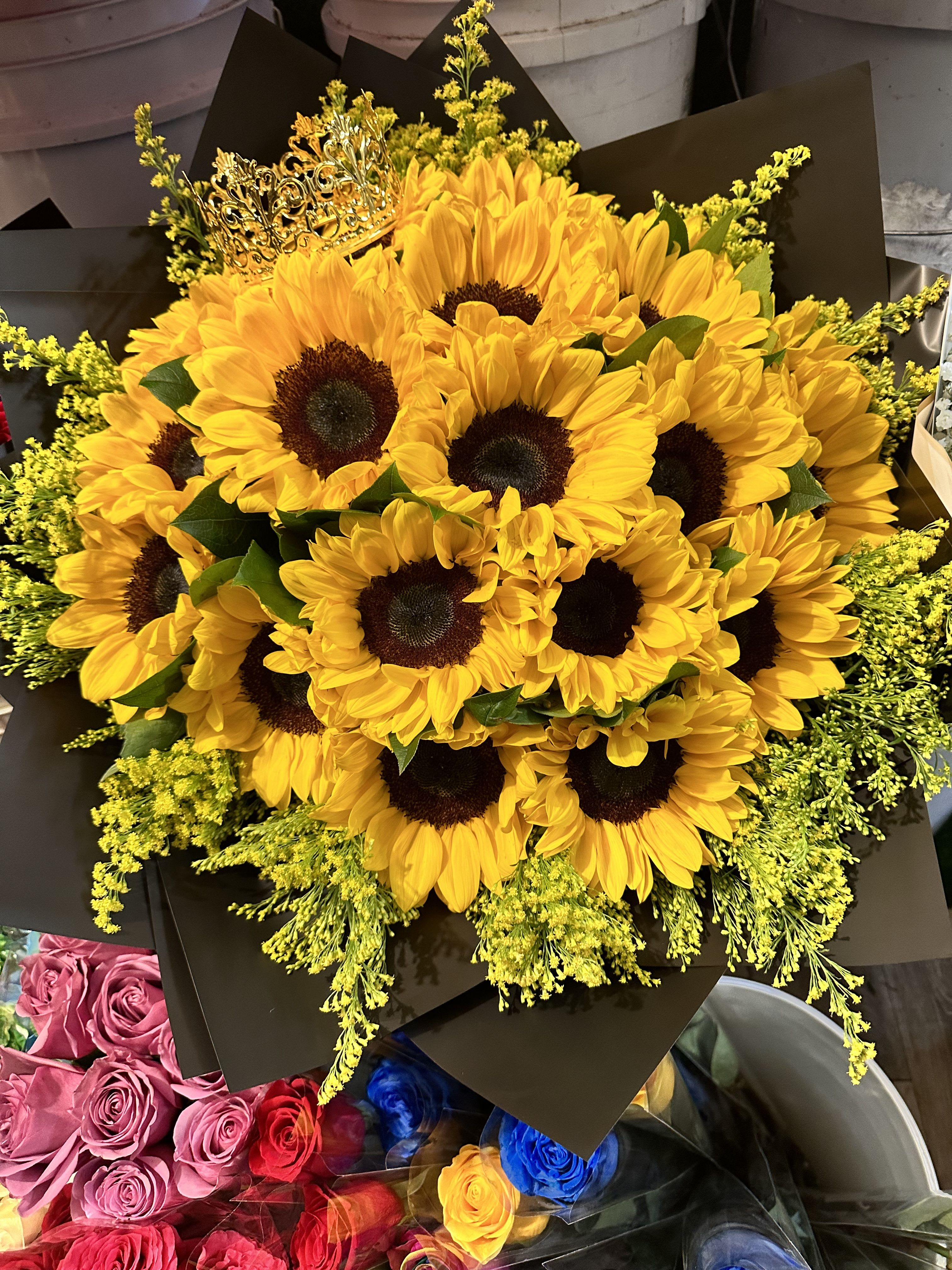 Bouquet of yellow sunflowers with dark wrapping and a decorative crown