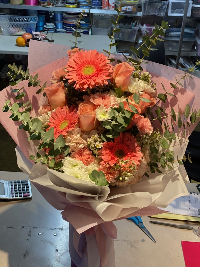 Peach bouquet with gerbera daisies and roses wrapped in pink paper