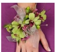 Green orchid wrist corsage with pink accents on a hand
