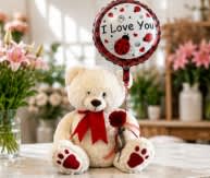 Teddy bear with a red ribbon holding an "I Love You" balloon