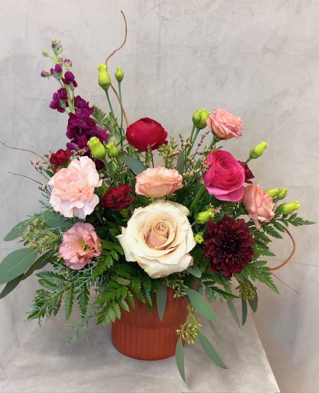 Mixed pink, cream, and burgundy flowers in a terracotta vase