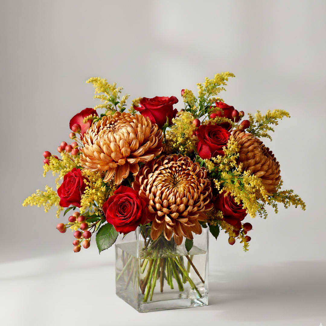 Red roses and bronze chrysanthemums in a clear glass vase