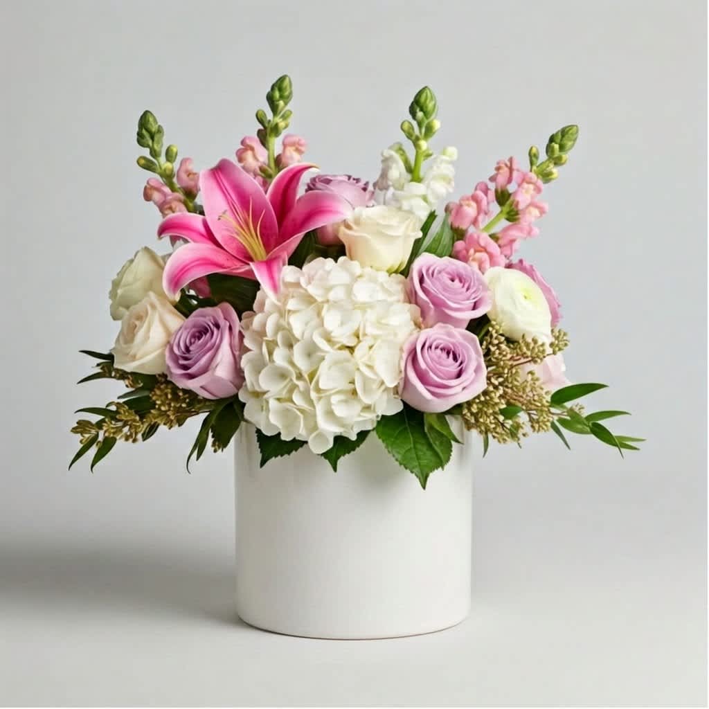 Pink lilies, roses, and white hydrangea in a white vase
