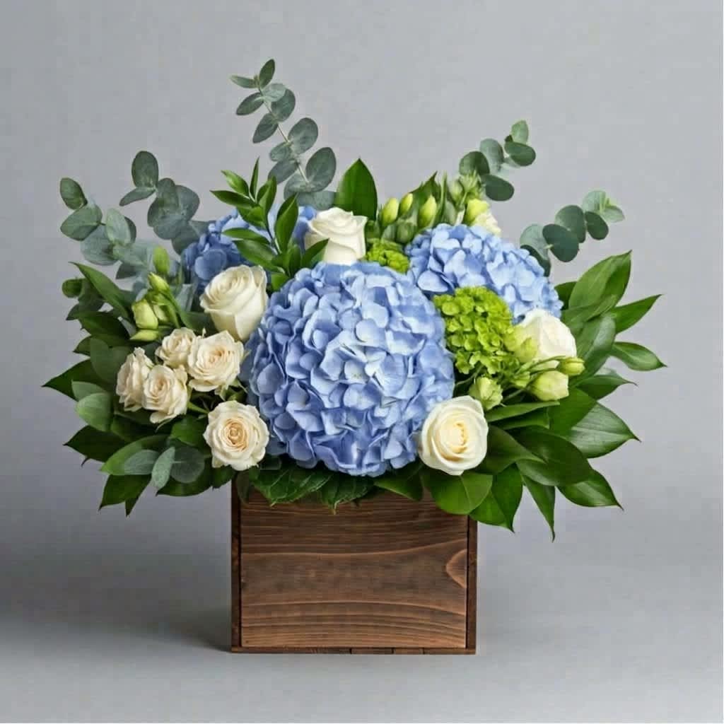 Blue hydrangeas and white roses arranged in a wooden box