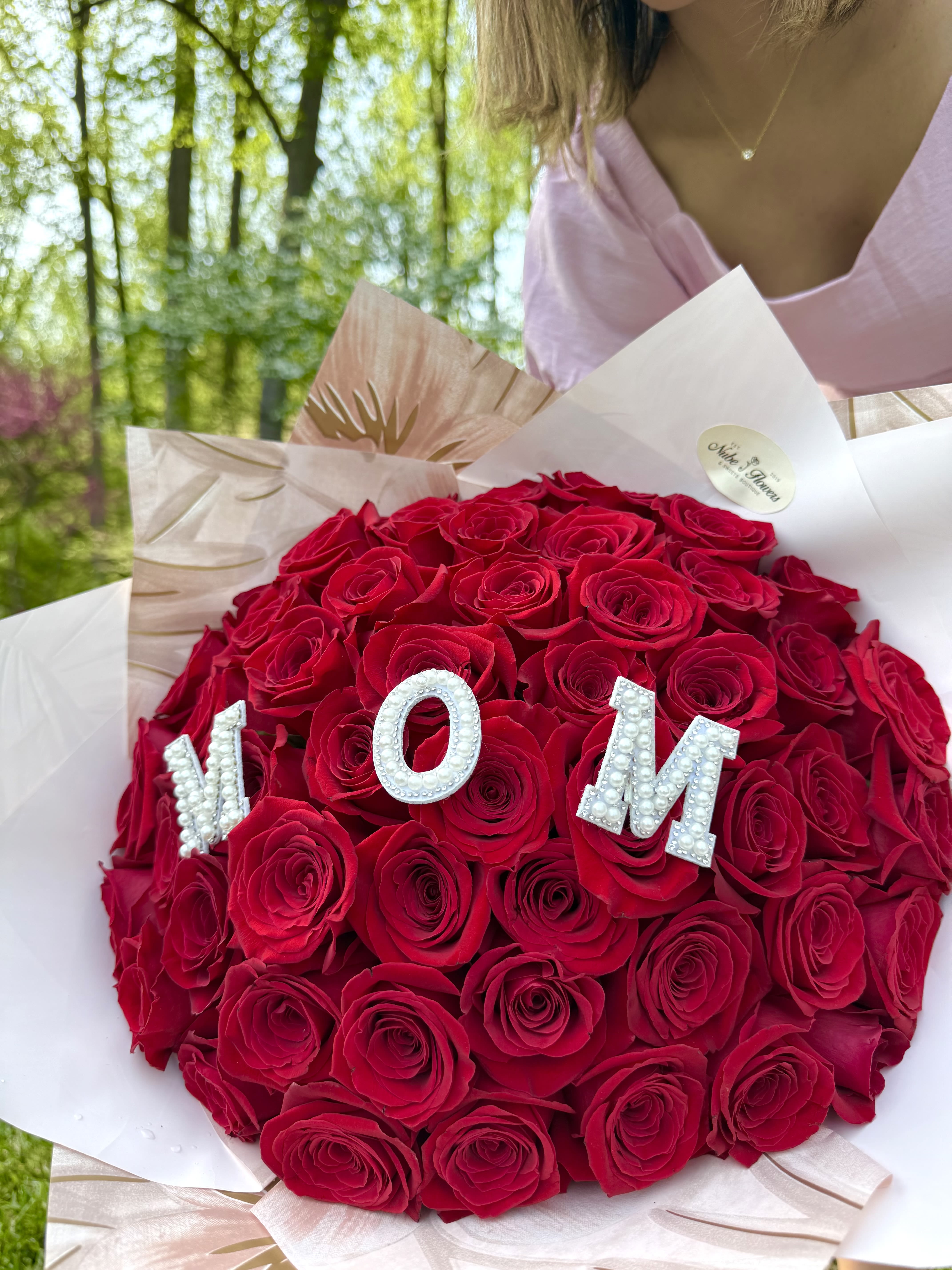 Round bouquet of red roses with pearl letters spelling MOM