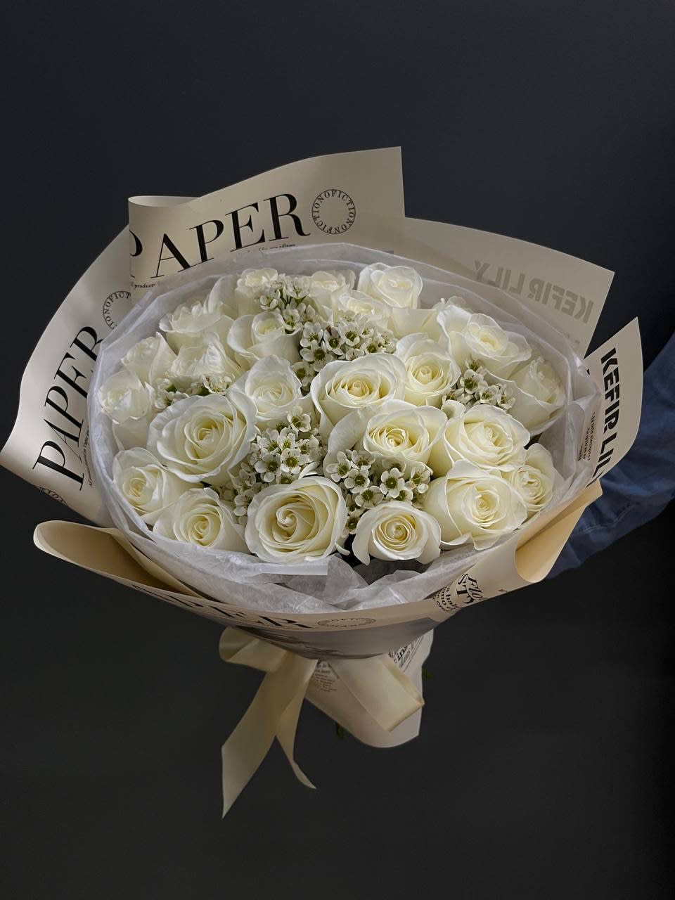 Bouquet of white roses wrapped in cream paper with a ribbon