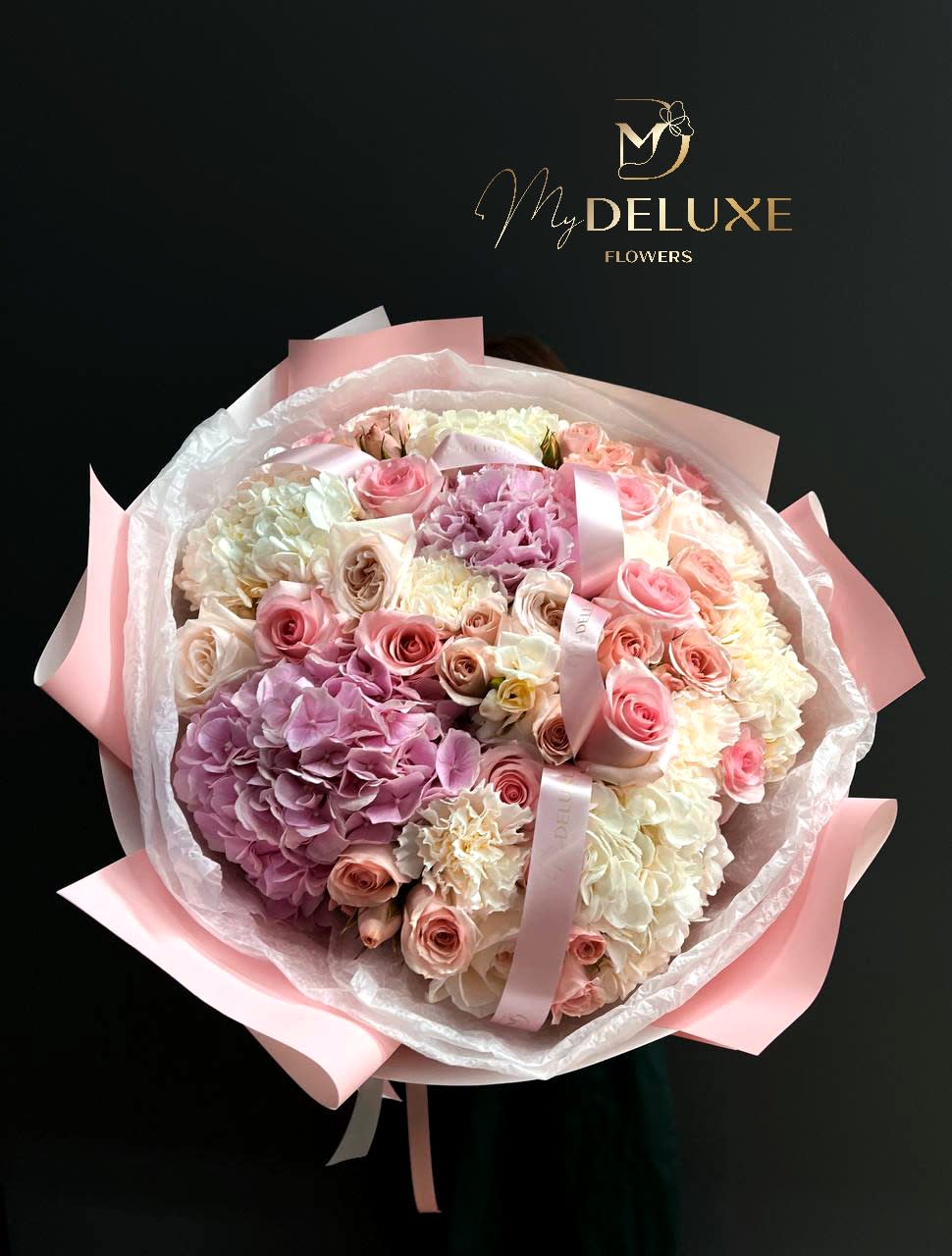 Large bouquet of pink and white roses and hydrangeas wrapped in pink paper
