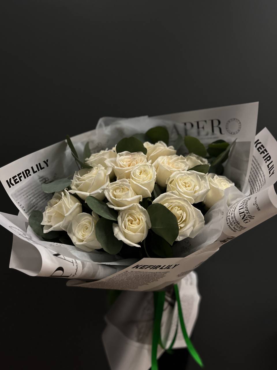 Bouquet of white roses wrapped in printed paper