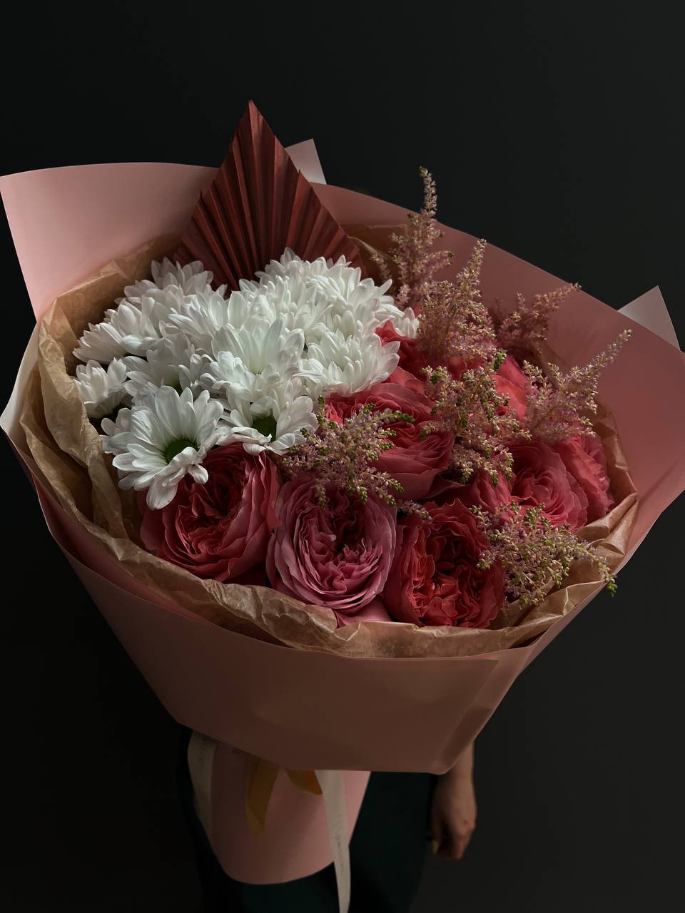 Bouquet of pink roses and white daisies wrapped in pink paper