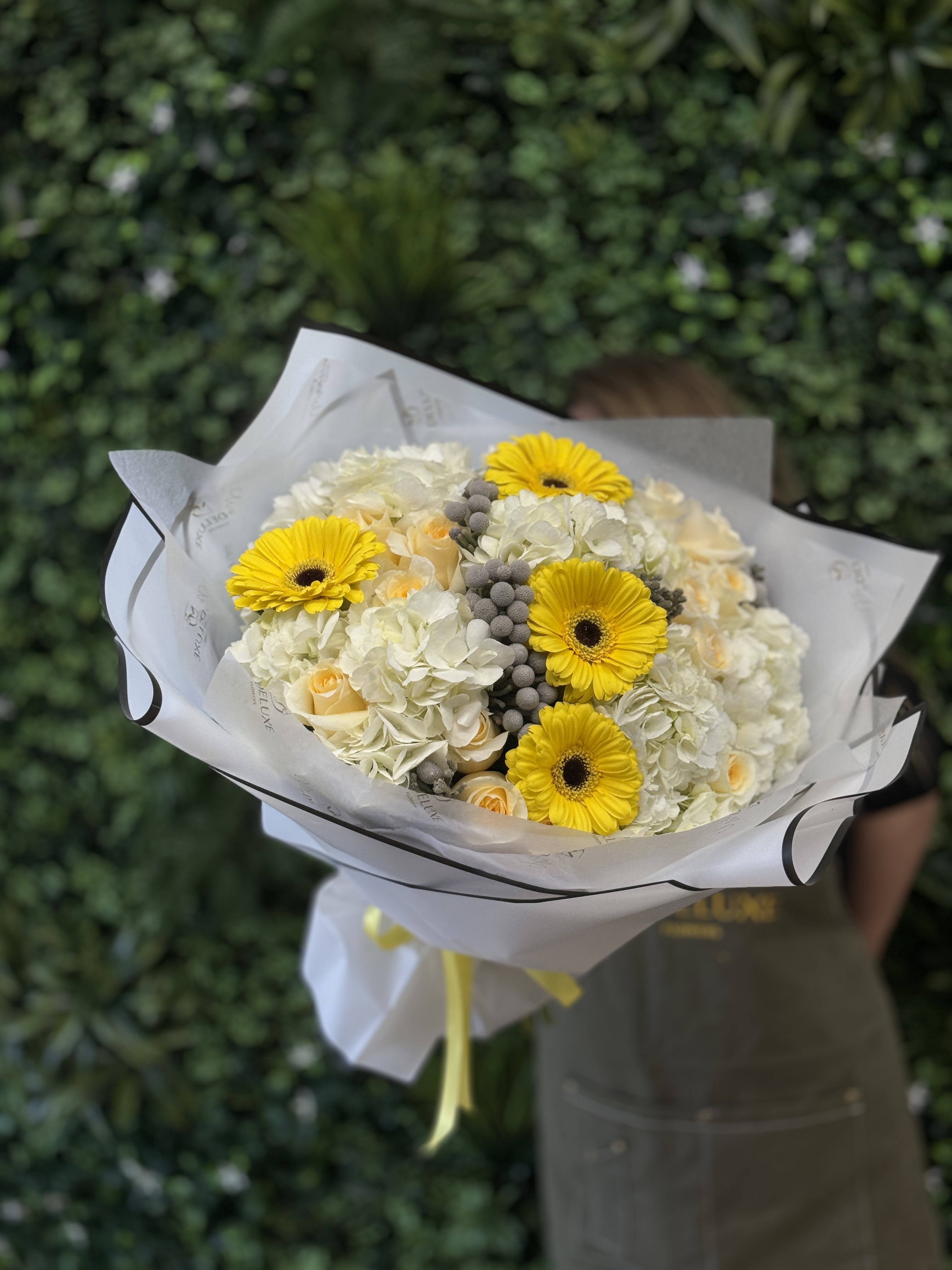 Bouquet of yellow gerbera daisies and white roses wrapped in white paper