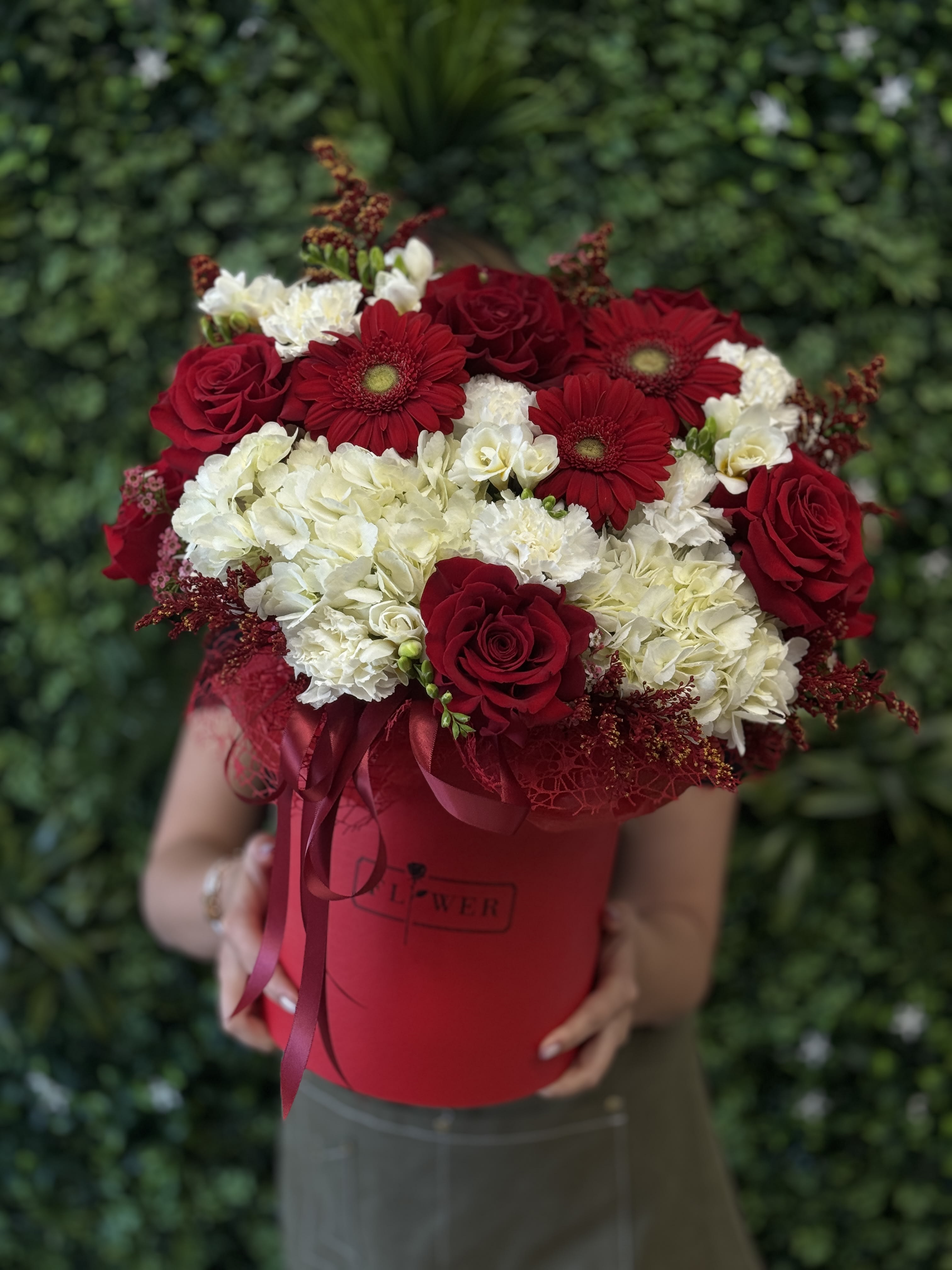 Red roses and white hydrangeas in a red hatbox