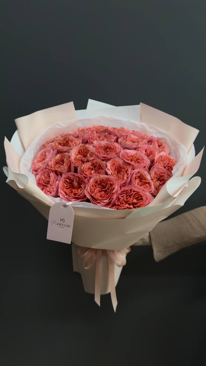 Bouquet of coral-pink roses wrapped in pale paper