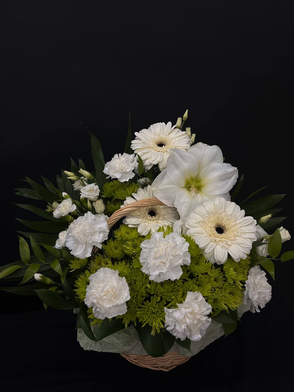 White flowers and green blooms arranged in a wicker basket