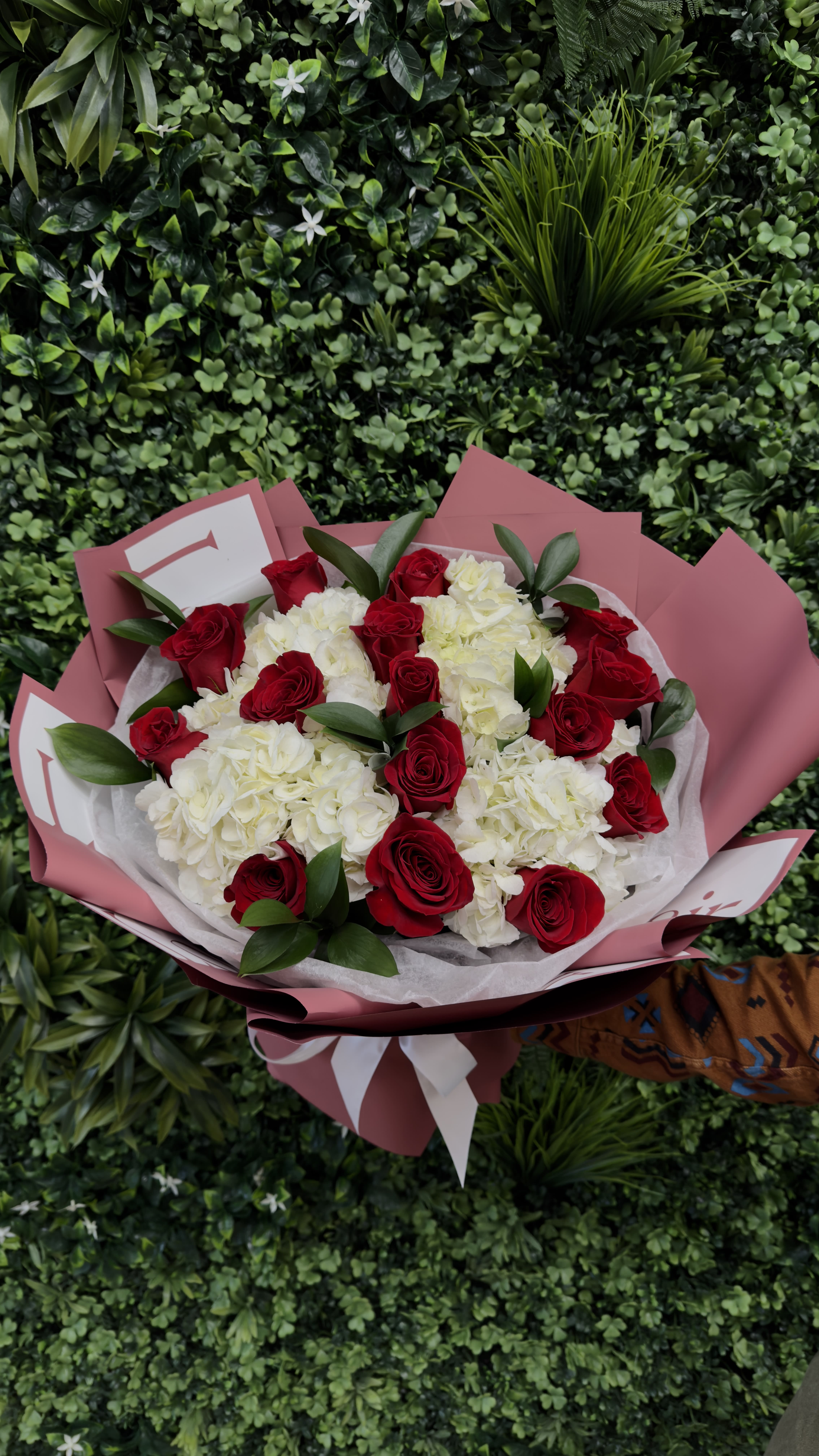 Bouquet of red roses and white hydrangeas wrapped in pink paper