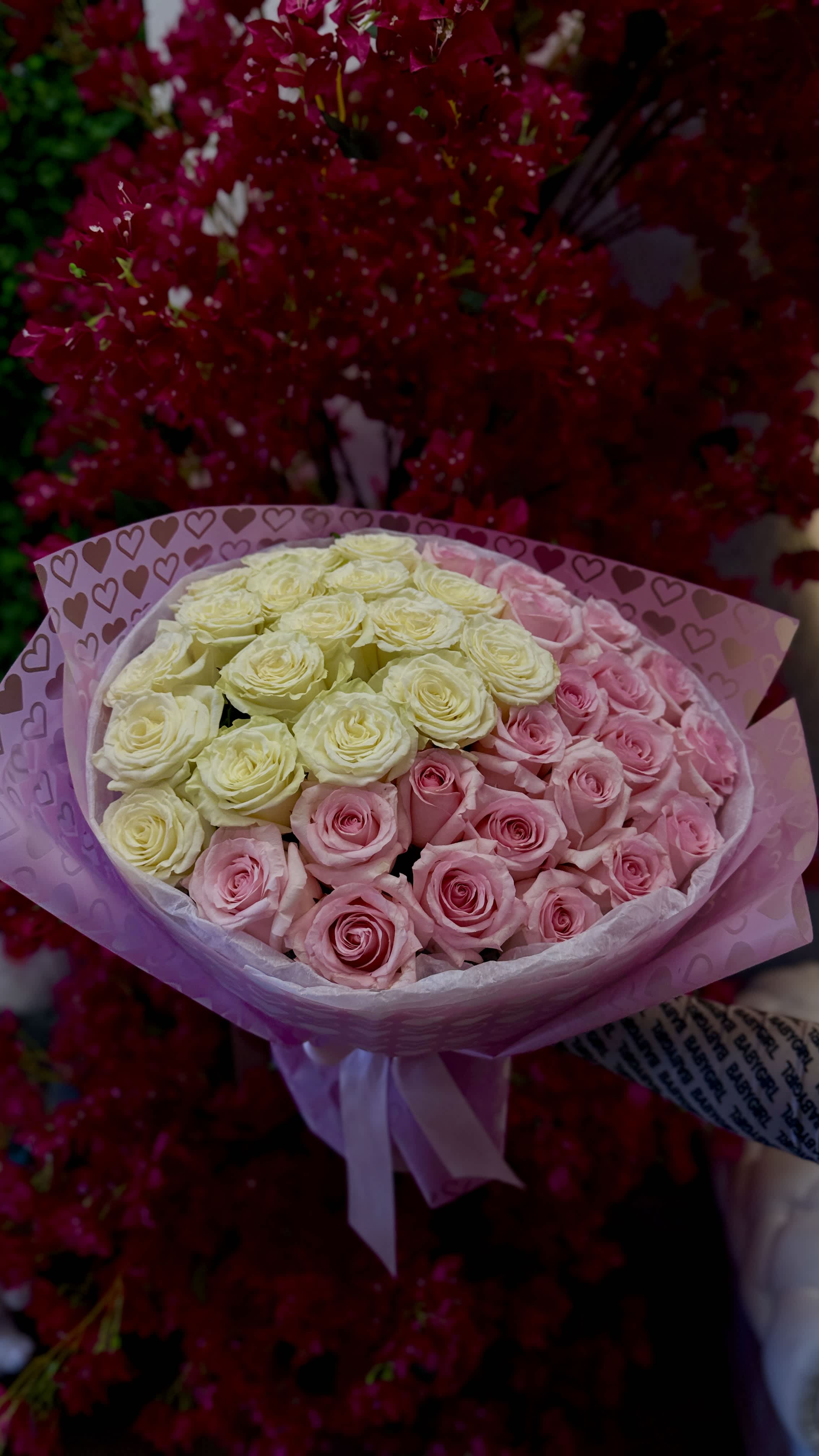 Bouquet of pink and cream roses wrapped in heart-patterned paper