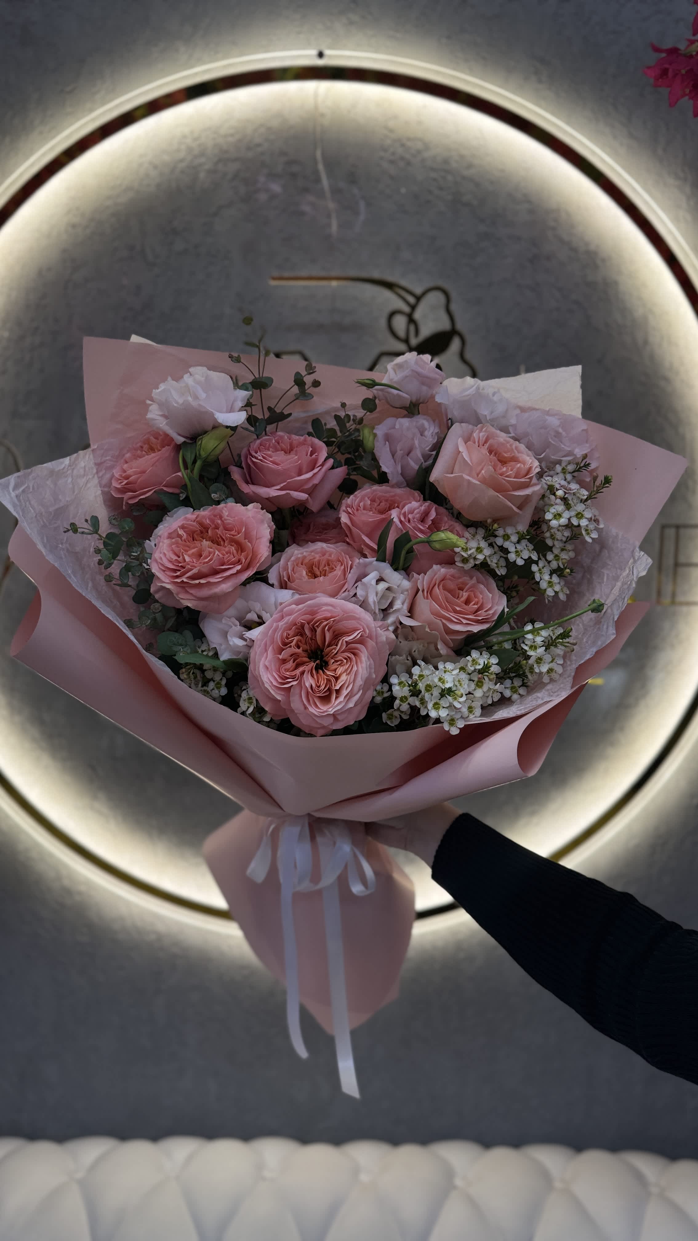 Pink rose bouquet wrapped in pastel paper with a white ribbon