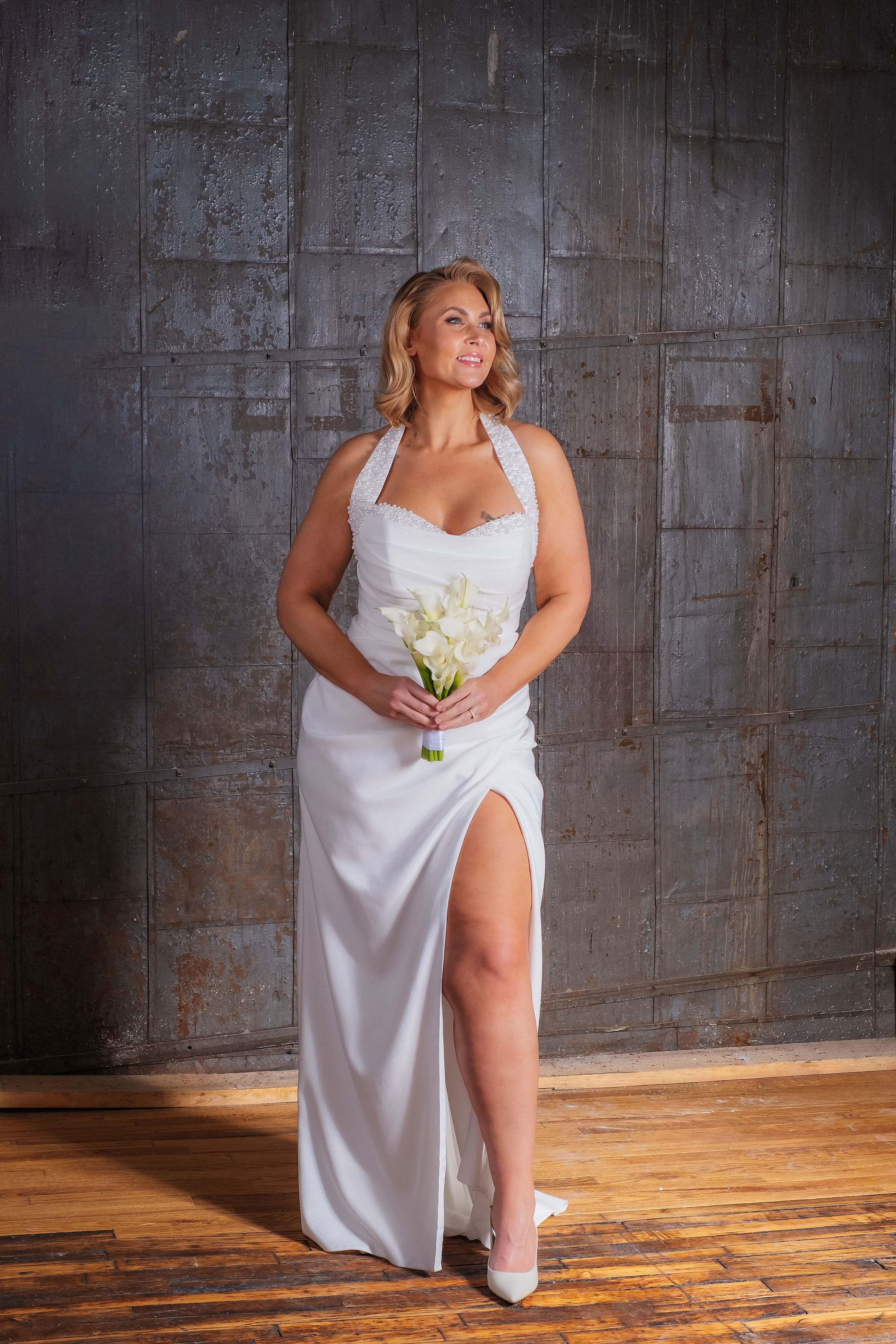 Bride in a white gown holding a small bouquet of white calla lilies