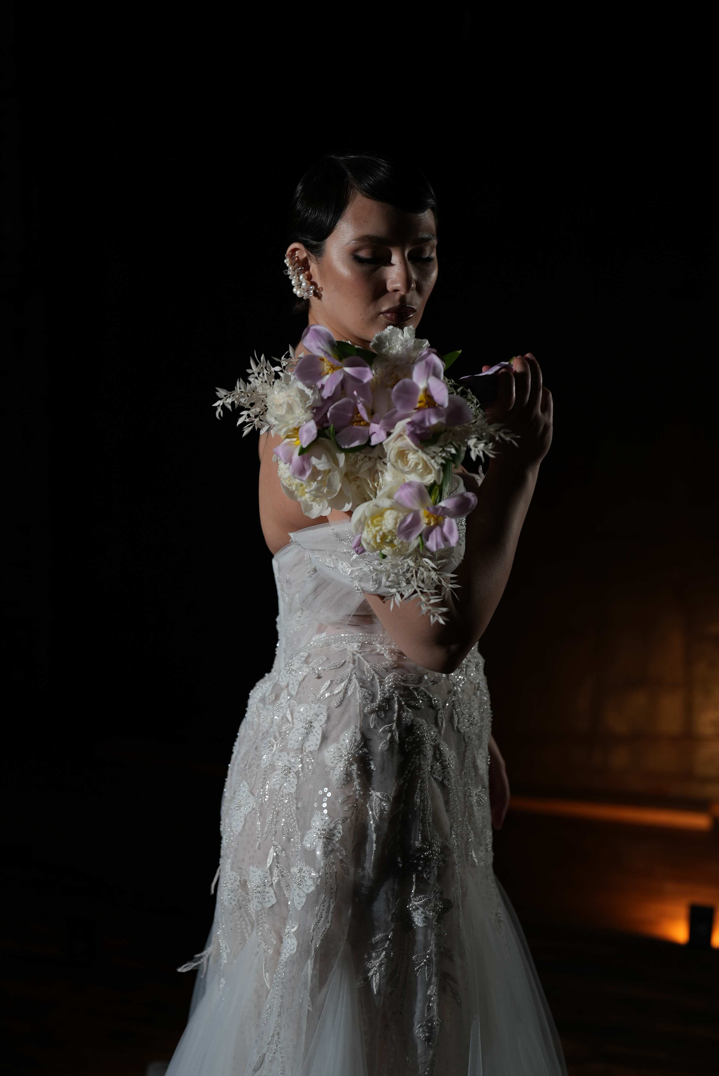 Bride in a white gown holding a lavender and white floral bouquet