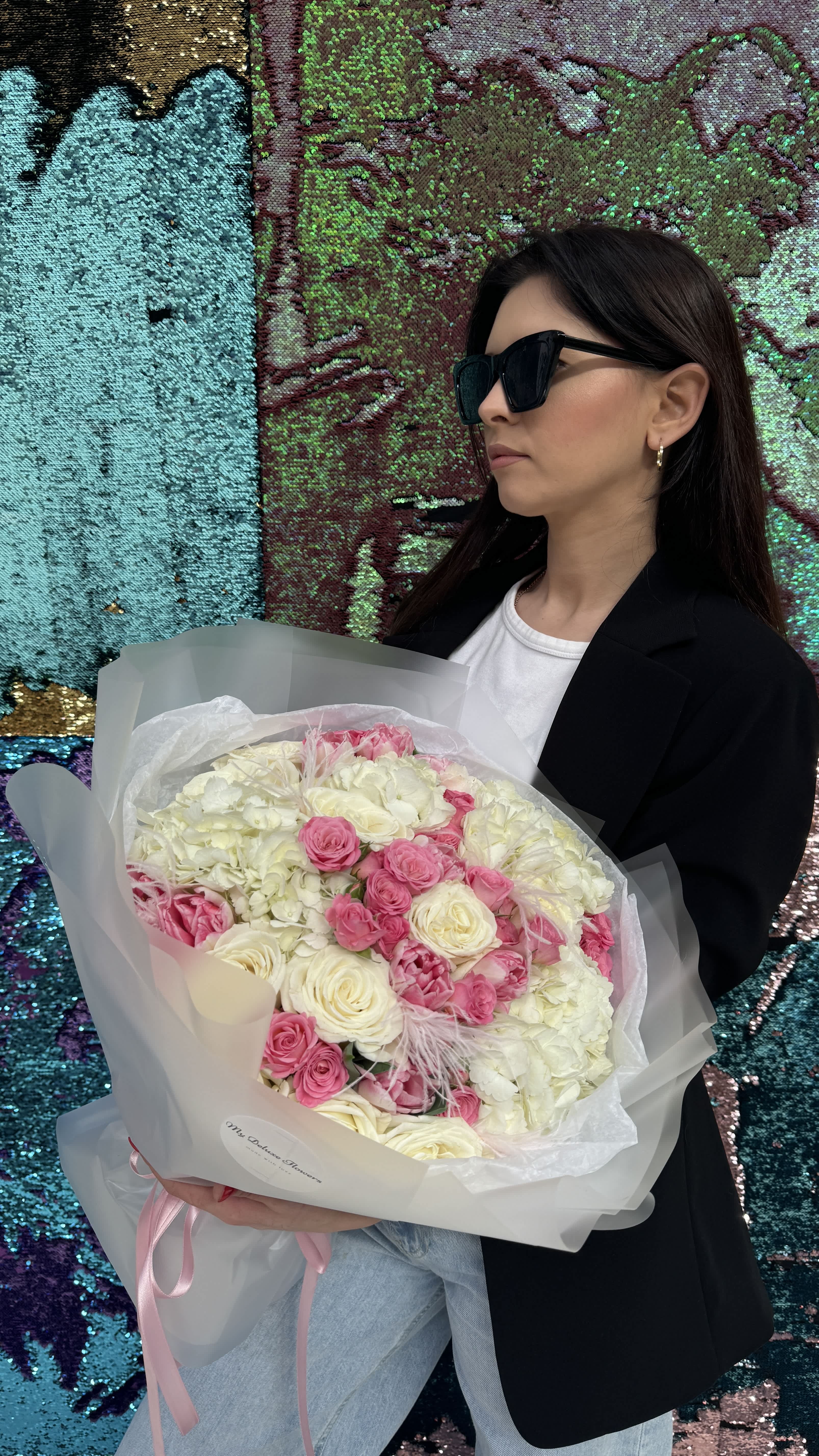 Woman holding a bouquet of pink and white flowers wrapped in translucent paper