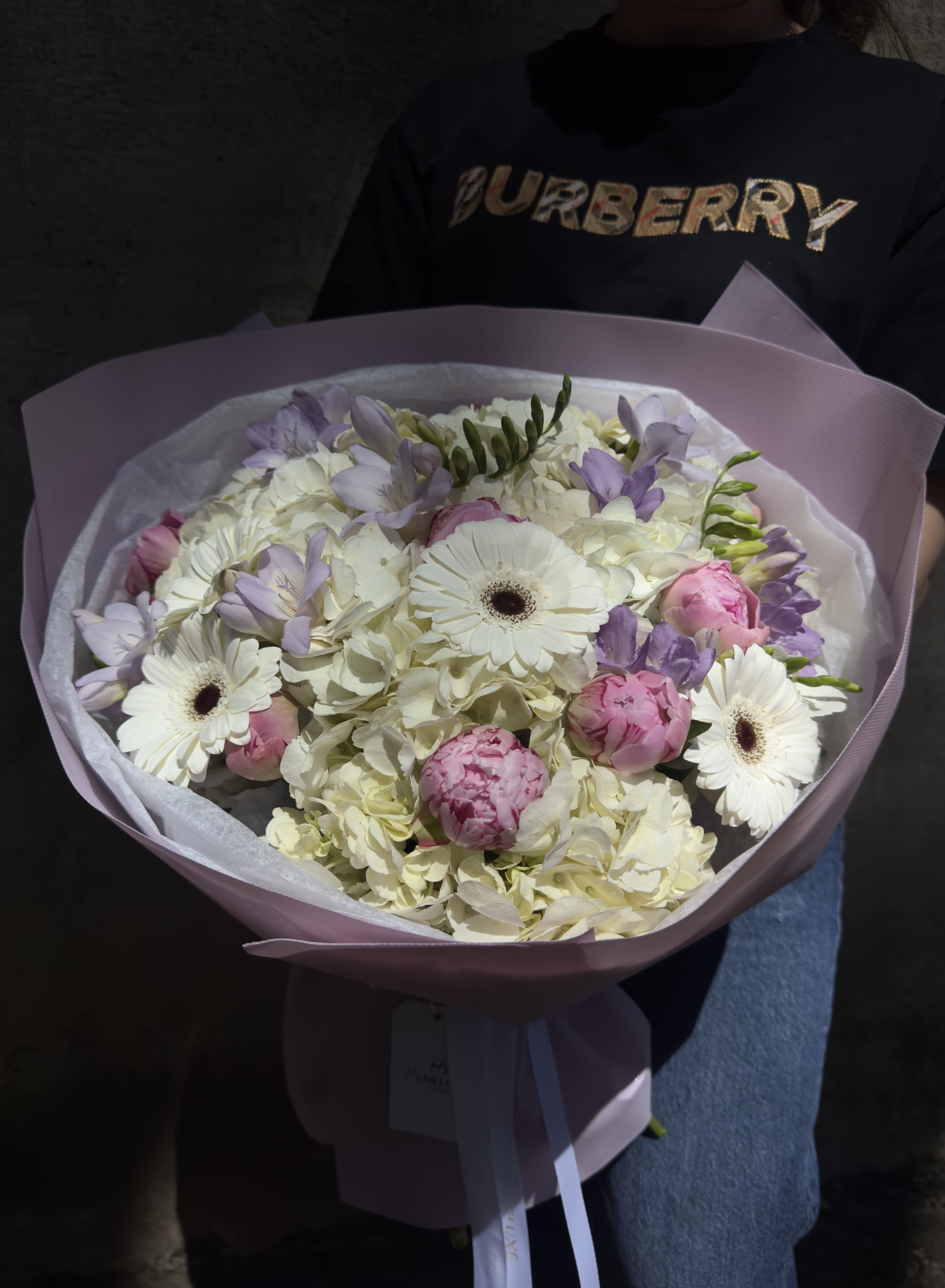 Bouquet of white and pink flowers wrapped in pale pink paper