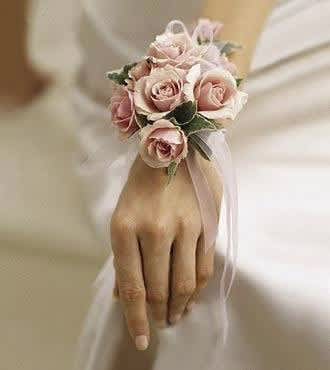Pink rose wrist corsage with ribbon on a hand