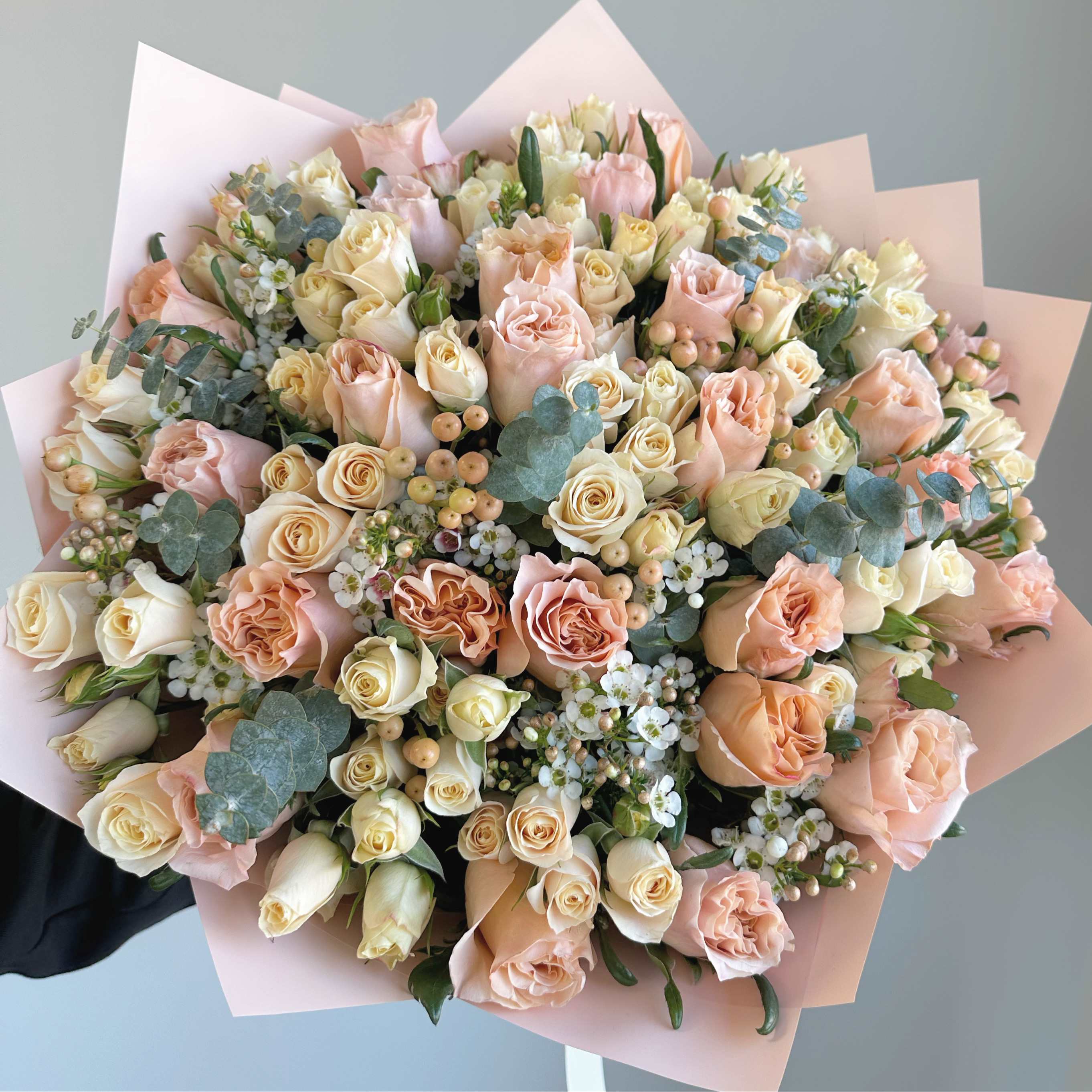 Large bouquet of blush and cream roses wrapped in pale pink paper