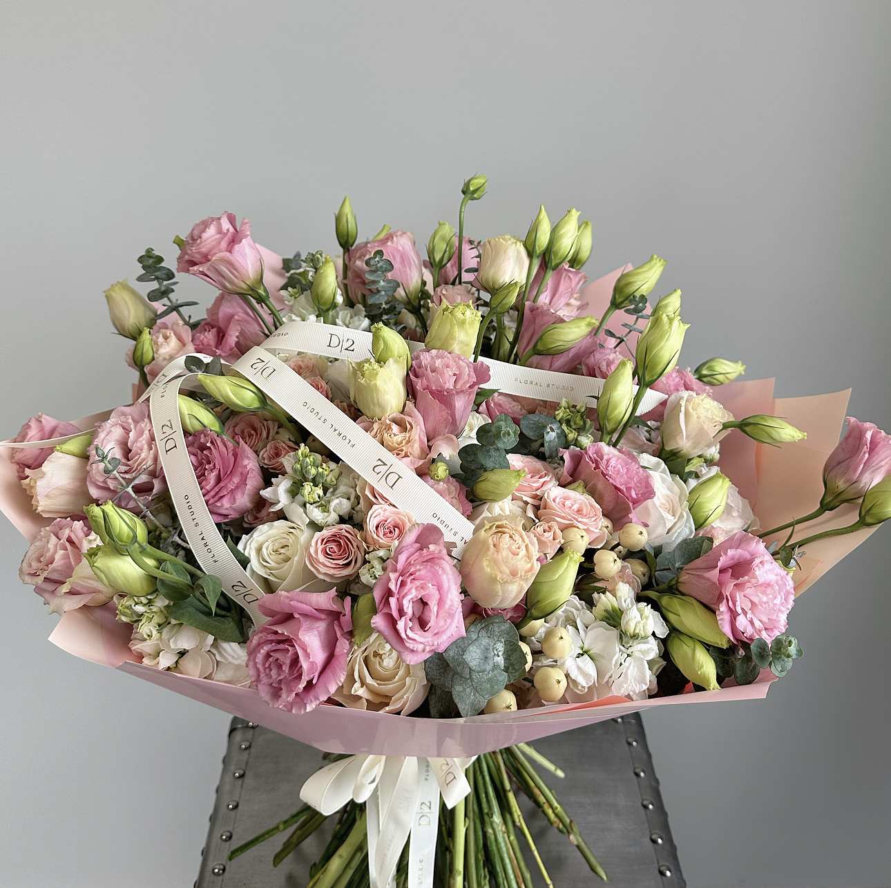 Large bouquet of pink and cream roses with white blooms wrapped in pink paper