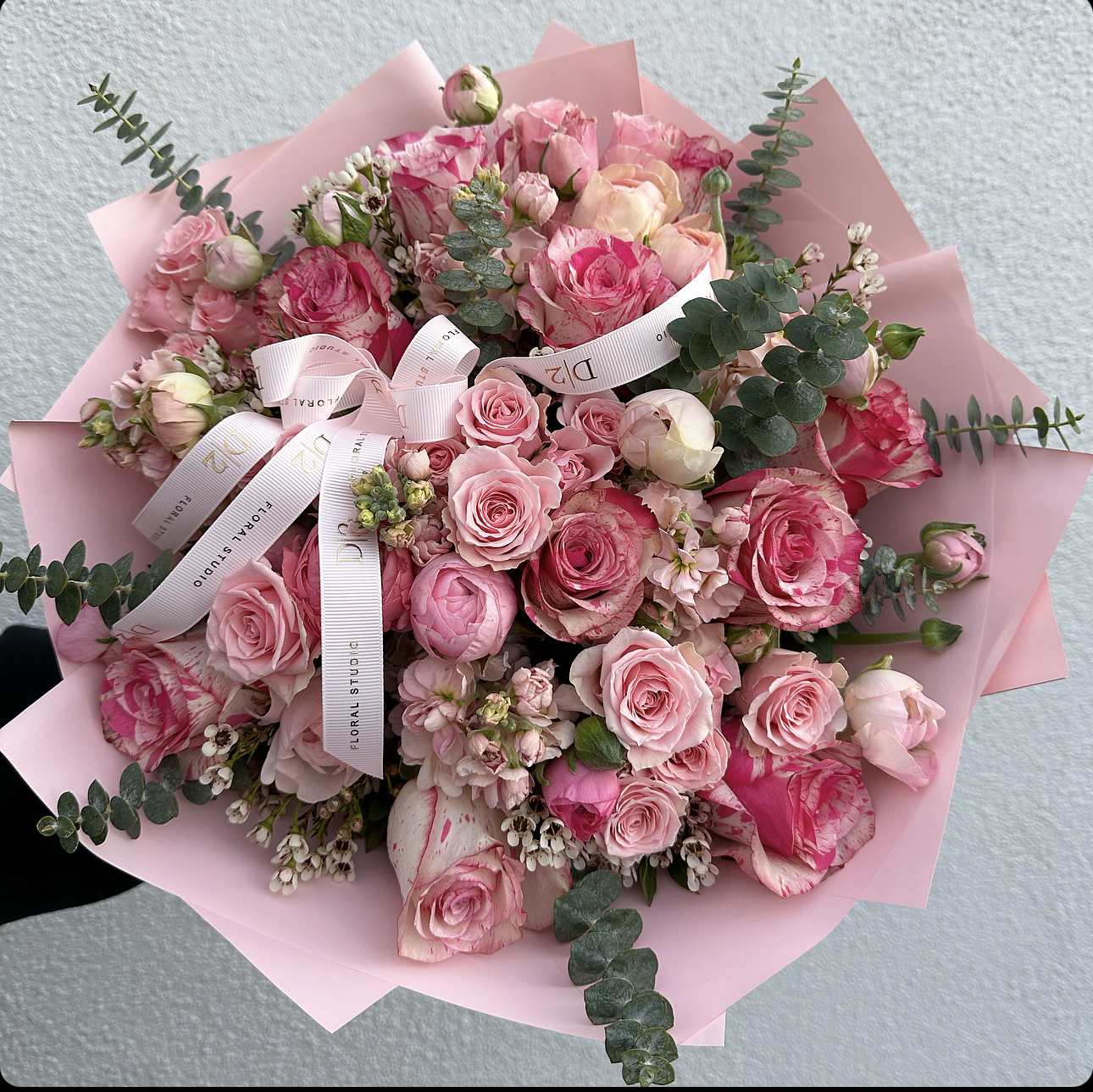 Pink rose bouquet wrapped in pale pink paper with ribbon