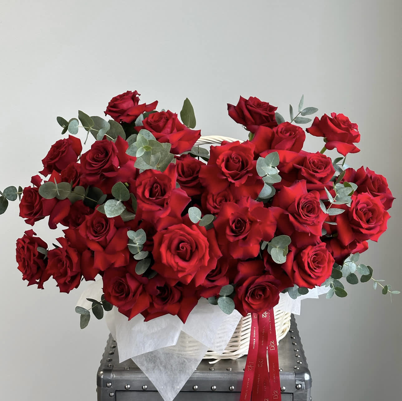 Basket of red roses with eucalyptus