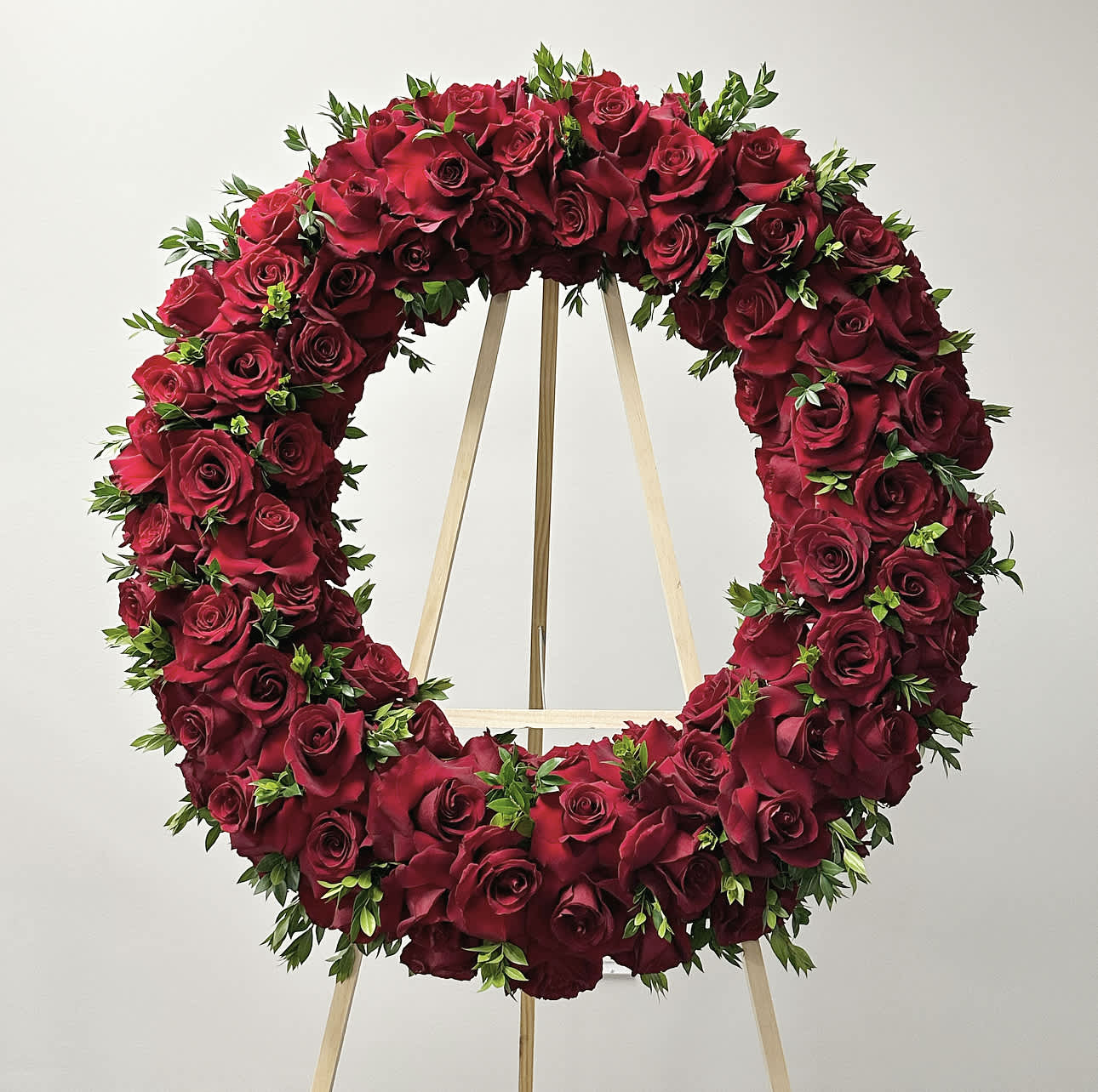 Circular wreath of red roses on a wooden stand