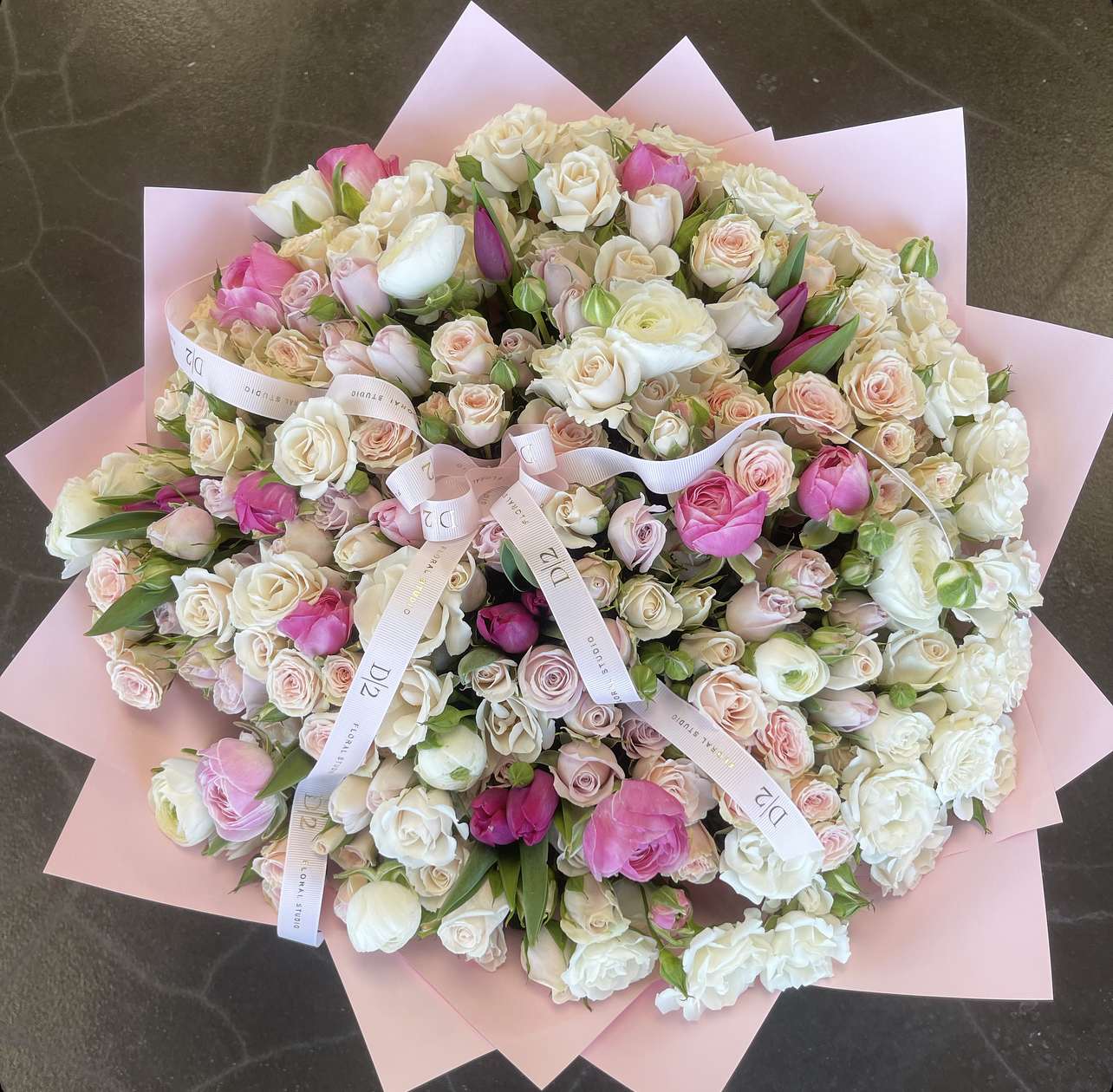 Large bouquet of pink and white roses wrapped in pale pink paper