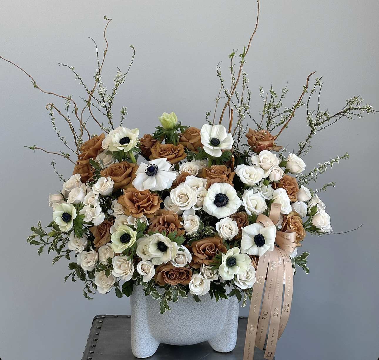 Large bouquet of white and brown roses with white anemones in a gray vase