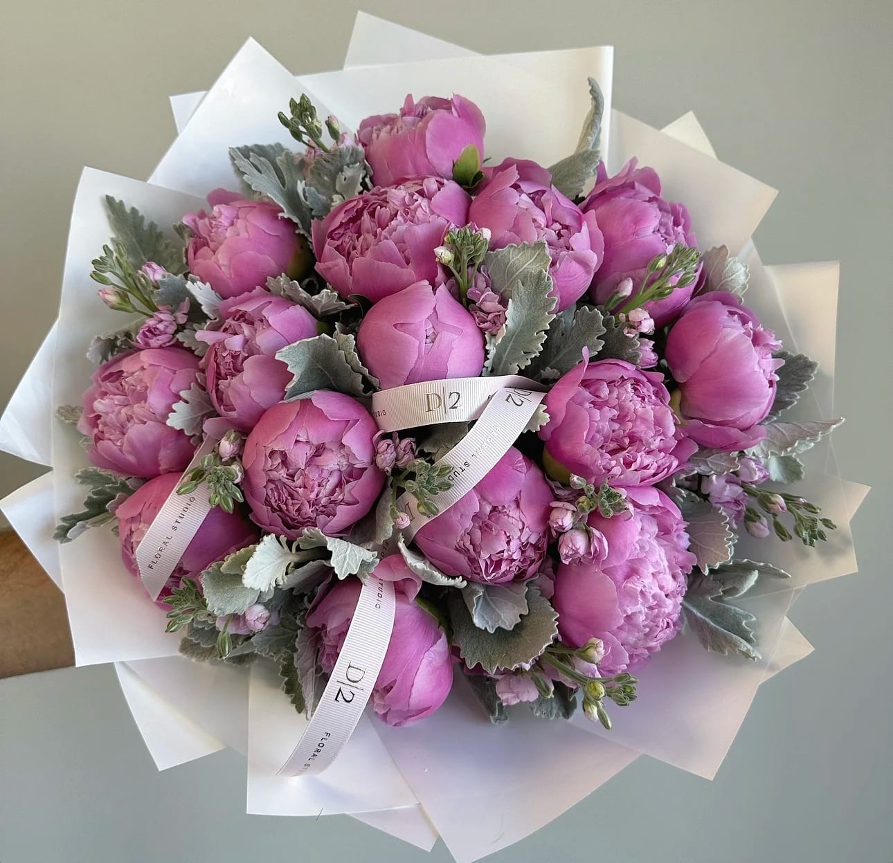 Pink peony bouquet wrapped in white paper with a ribbon