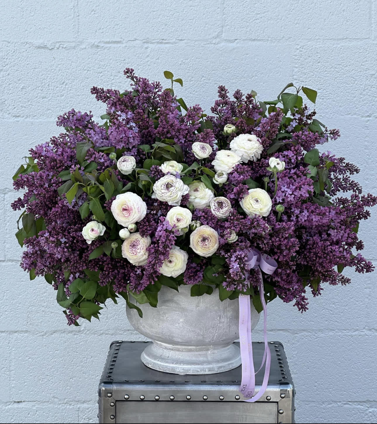 Large purple and white floral arrangement in a gray urn vase