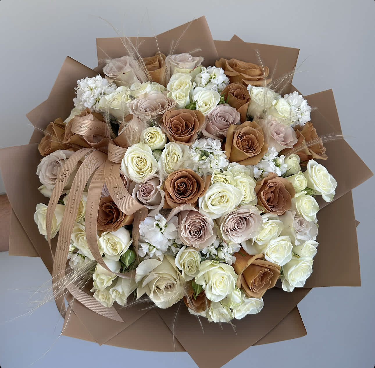 Bouquet of cream, blush, and caramel roses wrapped in brown paper