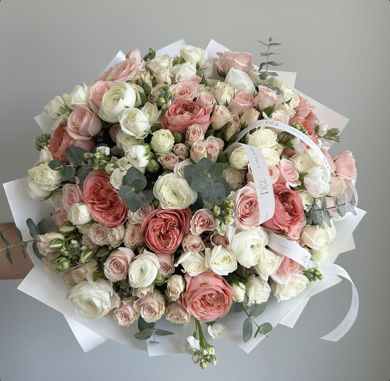 Large bouquet of pink and white roses wrapped in white paper