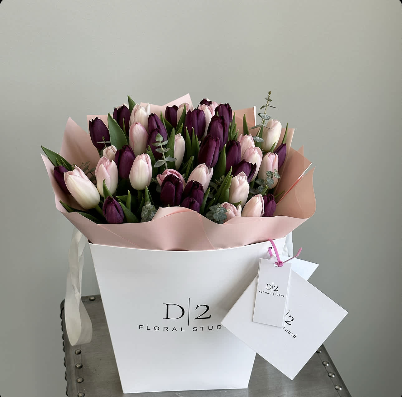Bouquet of pink and deep purple tulips in a white box