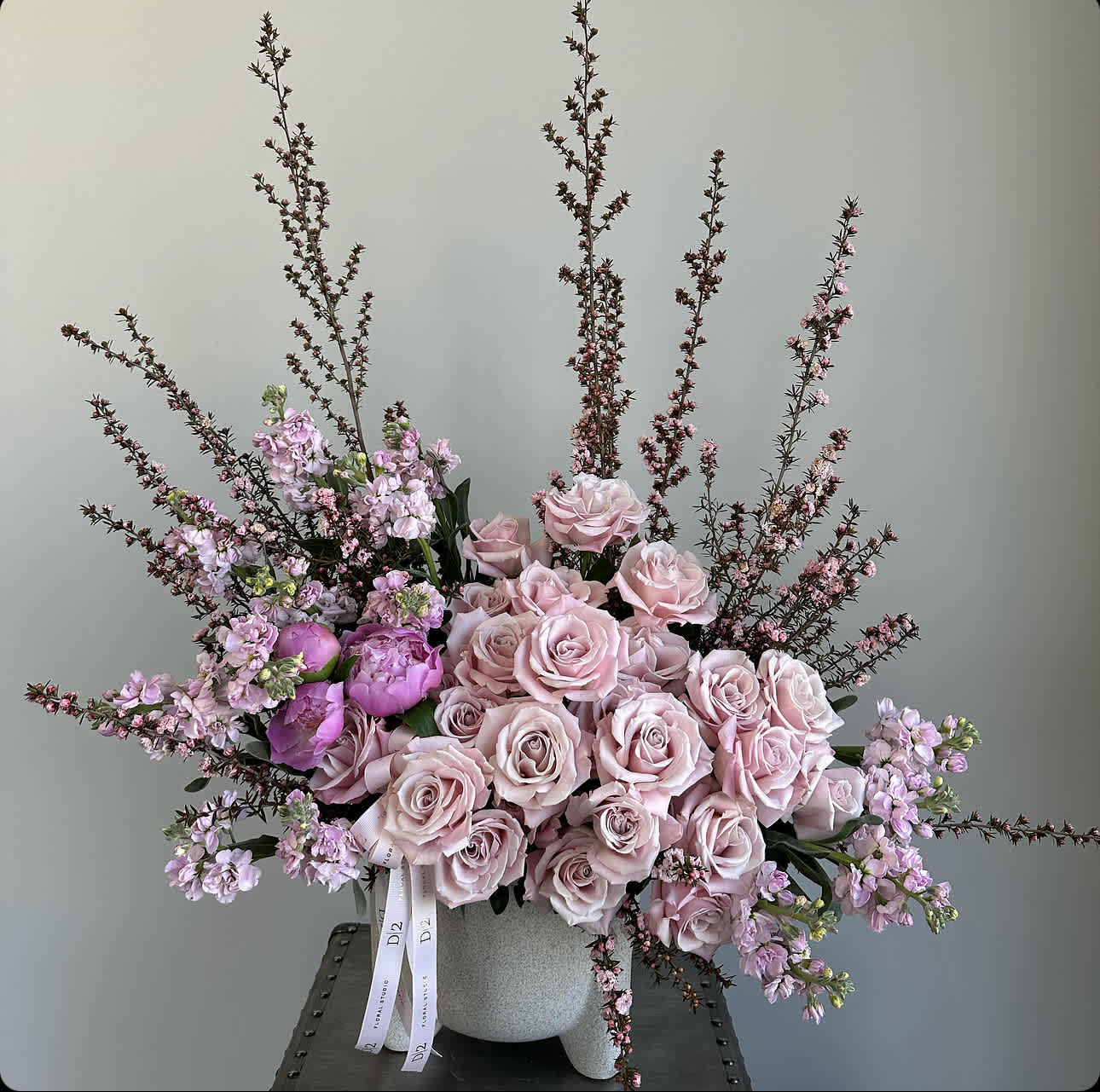 Pink roses and lilac flowers arranged in a gray vase