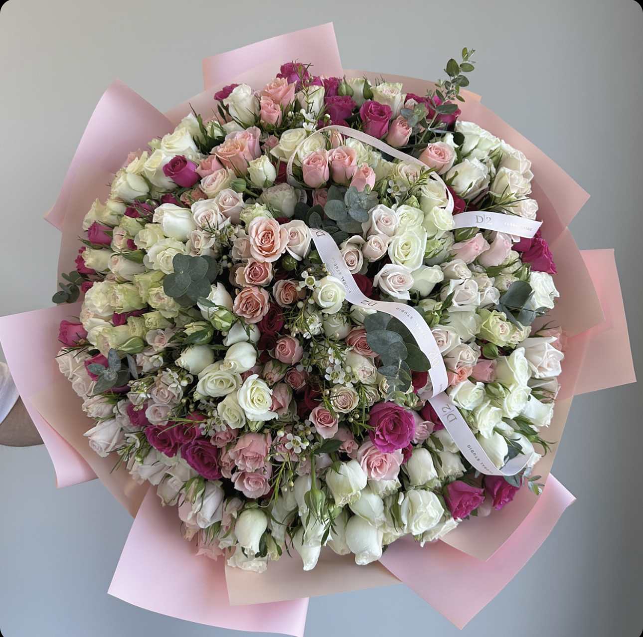 Large bouquet of pink, white, and magenta roses wrapped in pink paper
